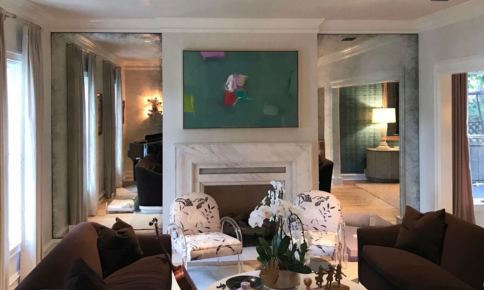 A living room with a fireplace , couch , chairs and a antique mirrors  on the wall.