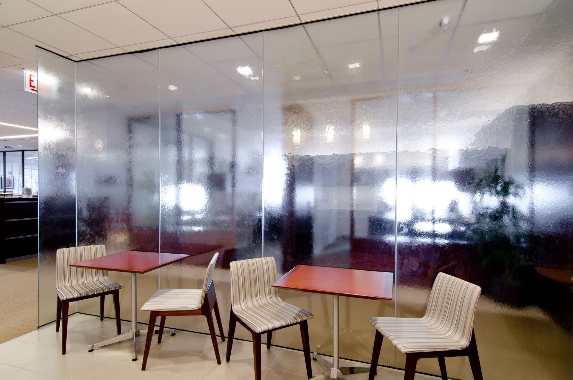 Modern office lounge with frosted glass walls and small tables with chairs