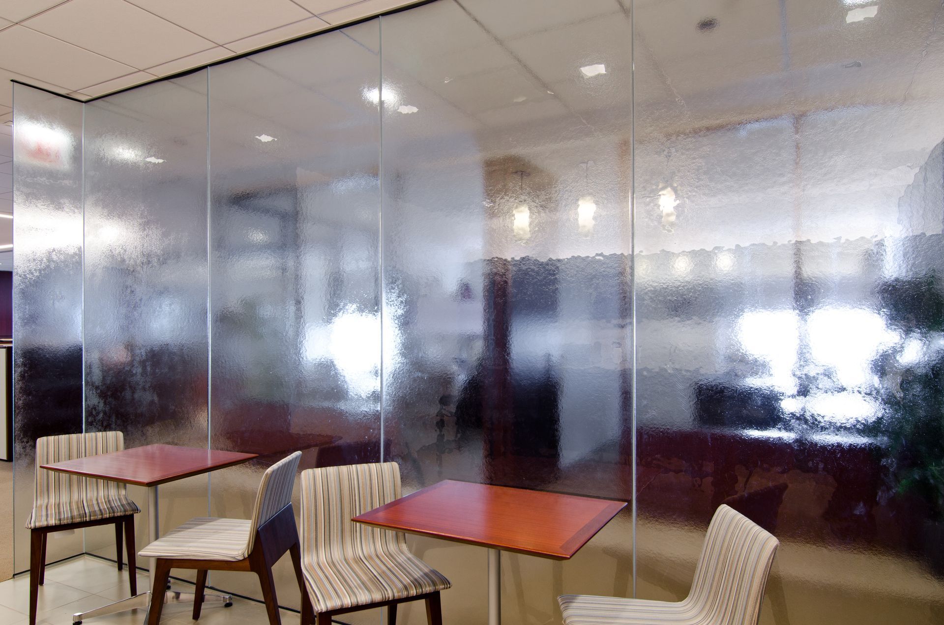 Empty office seating area with chairs and a small table beside frosted glass partitions