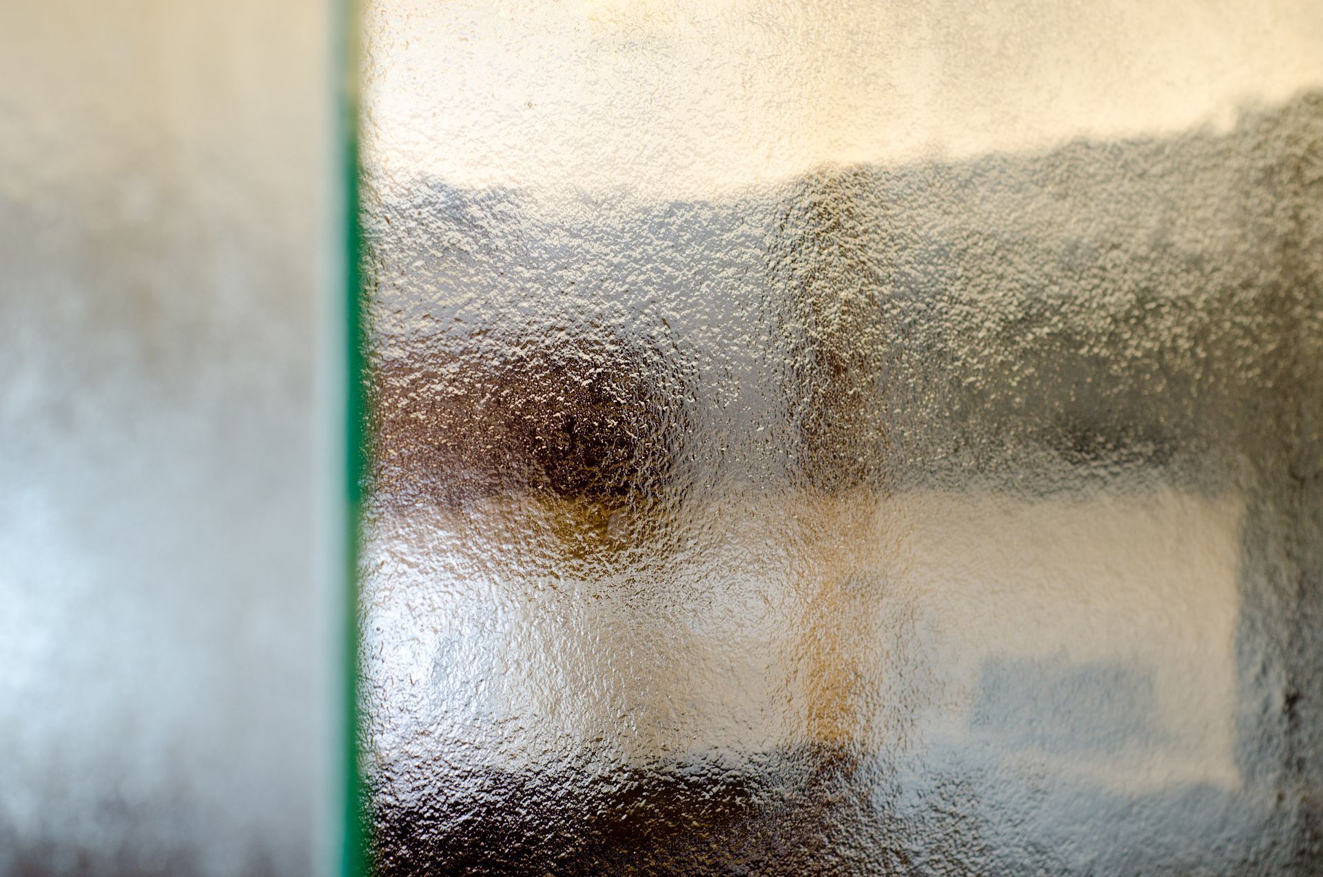 Frosted glass window with a blurred view of a room beyond and a green frame on the left
