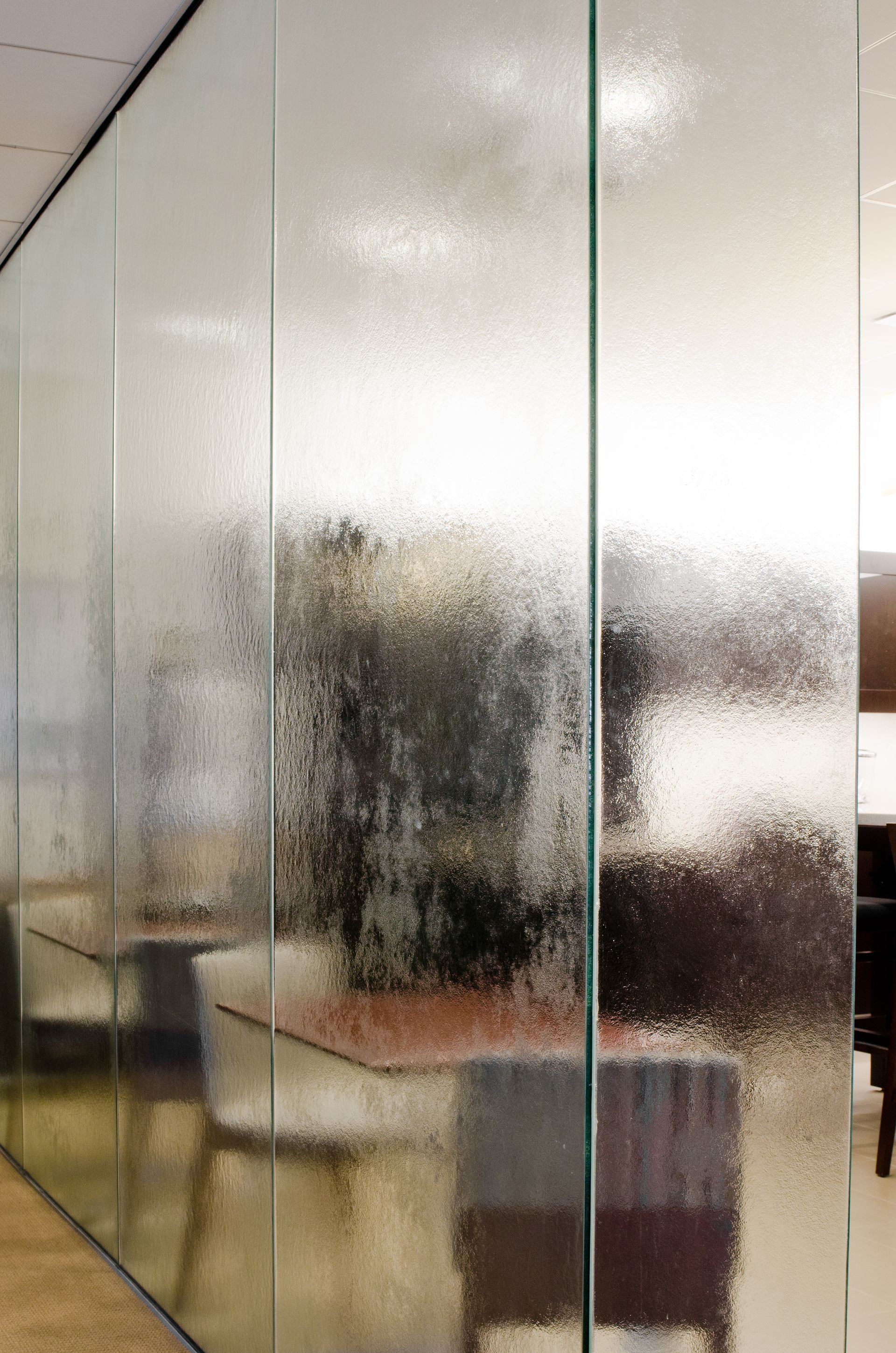 Frosted glass partition obscuring a room with chairs and a table behind it