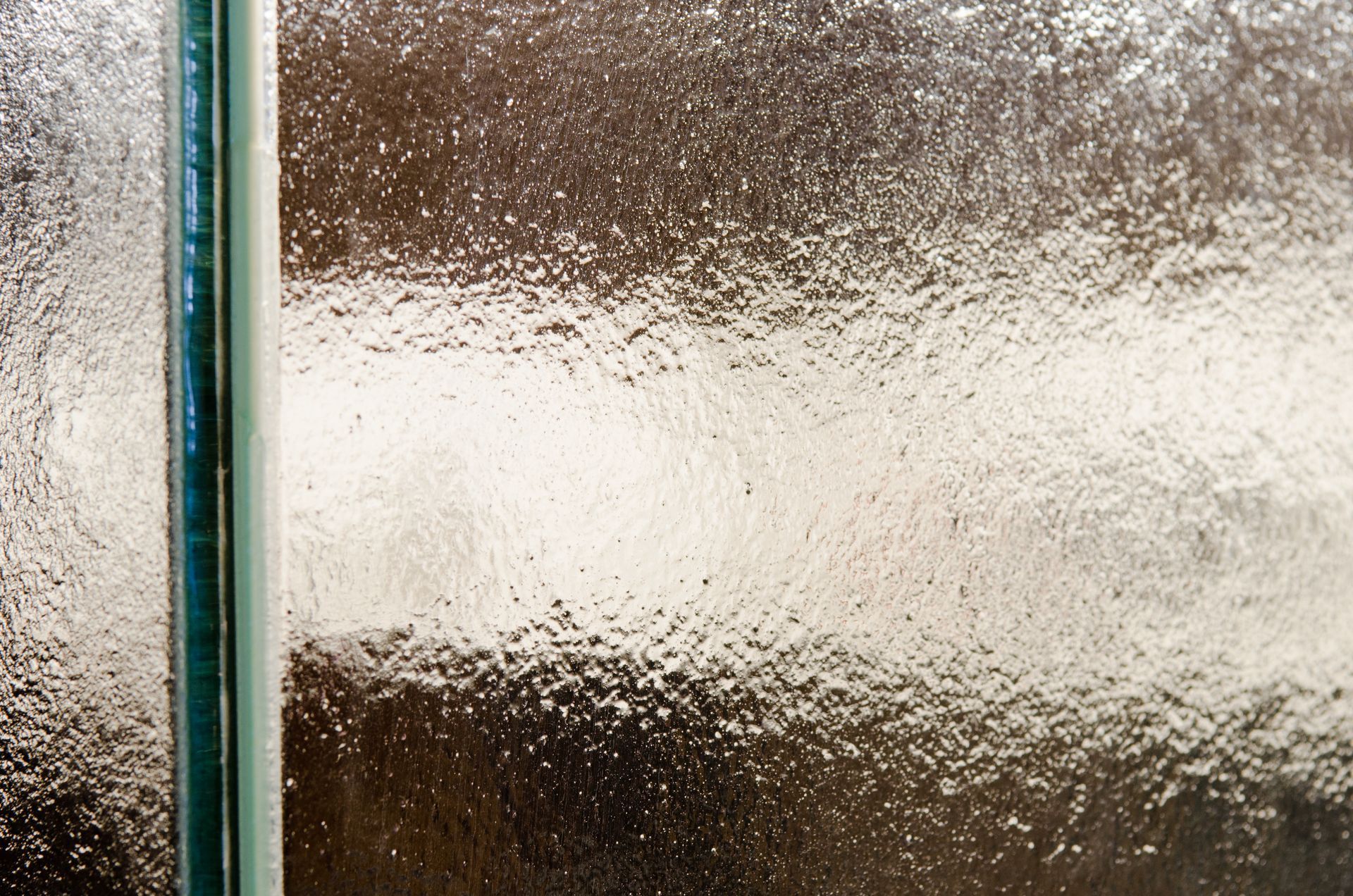 Frosted glass window with a vertical metal frame and blurred light behind it