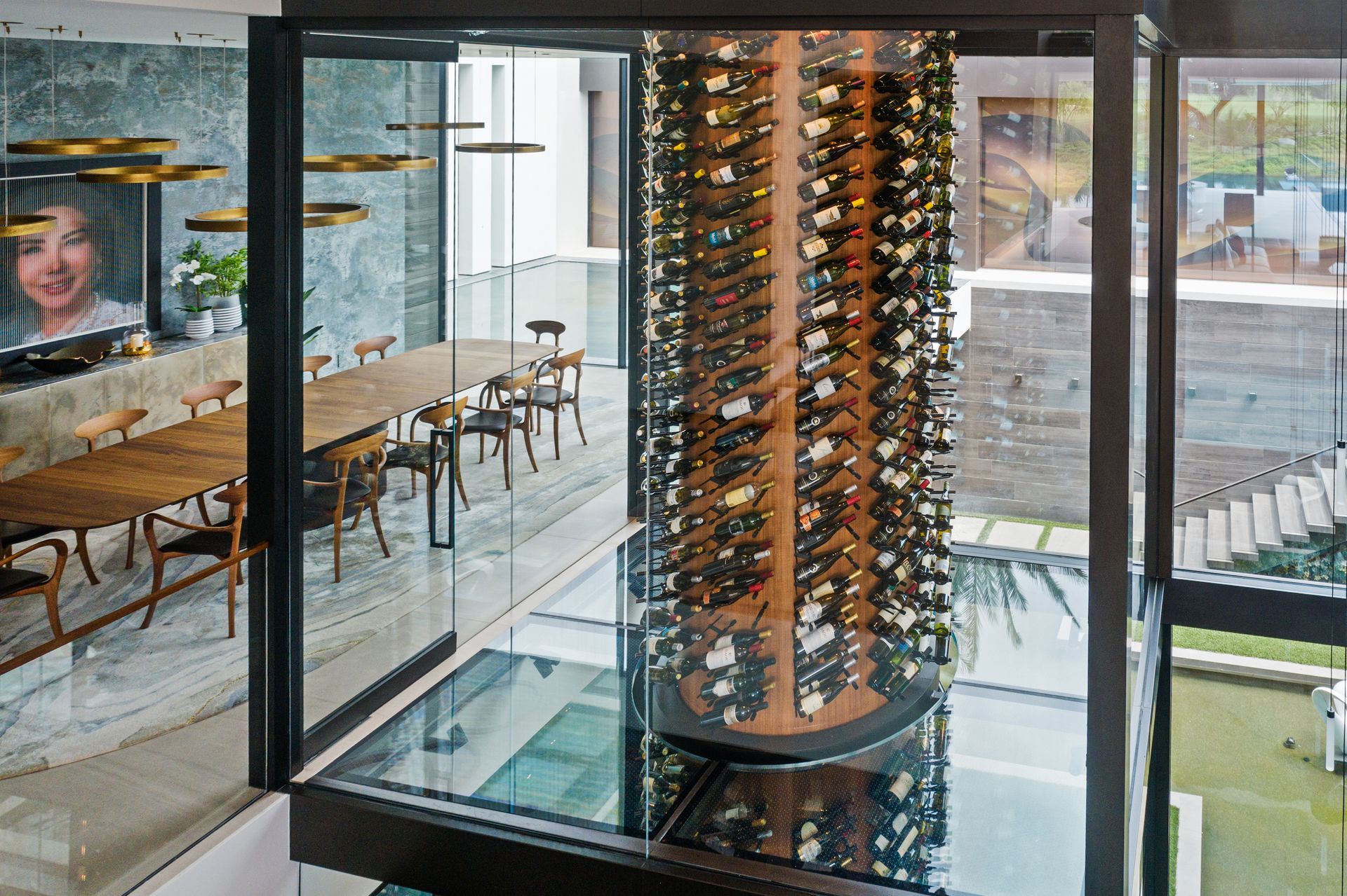 Modern wine tower in a glass atrium beside a lounge and patio seating