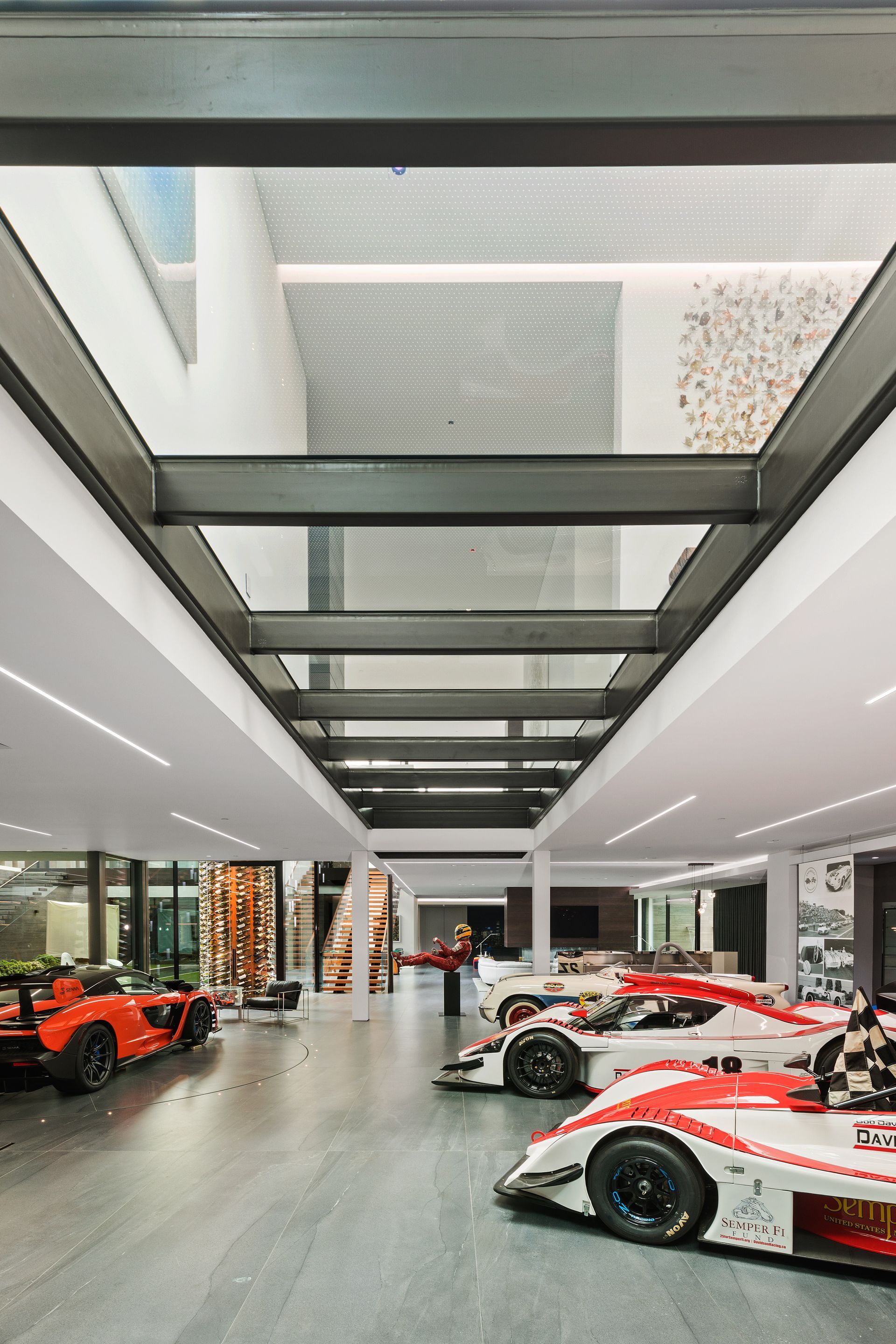 Luxury car showroom with several red and white race cars on display under a modern ceiling