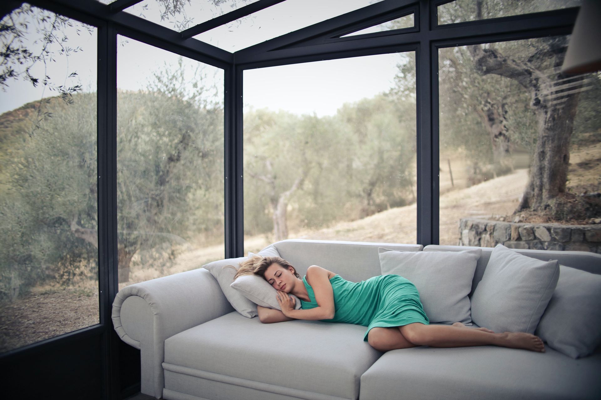 A woman sitting on a couch in a room surrounded by glass walls. A woman sitting on a couch in a room surrounded by glass walls.