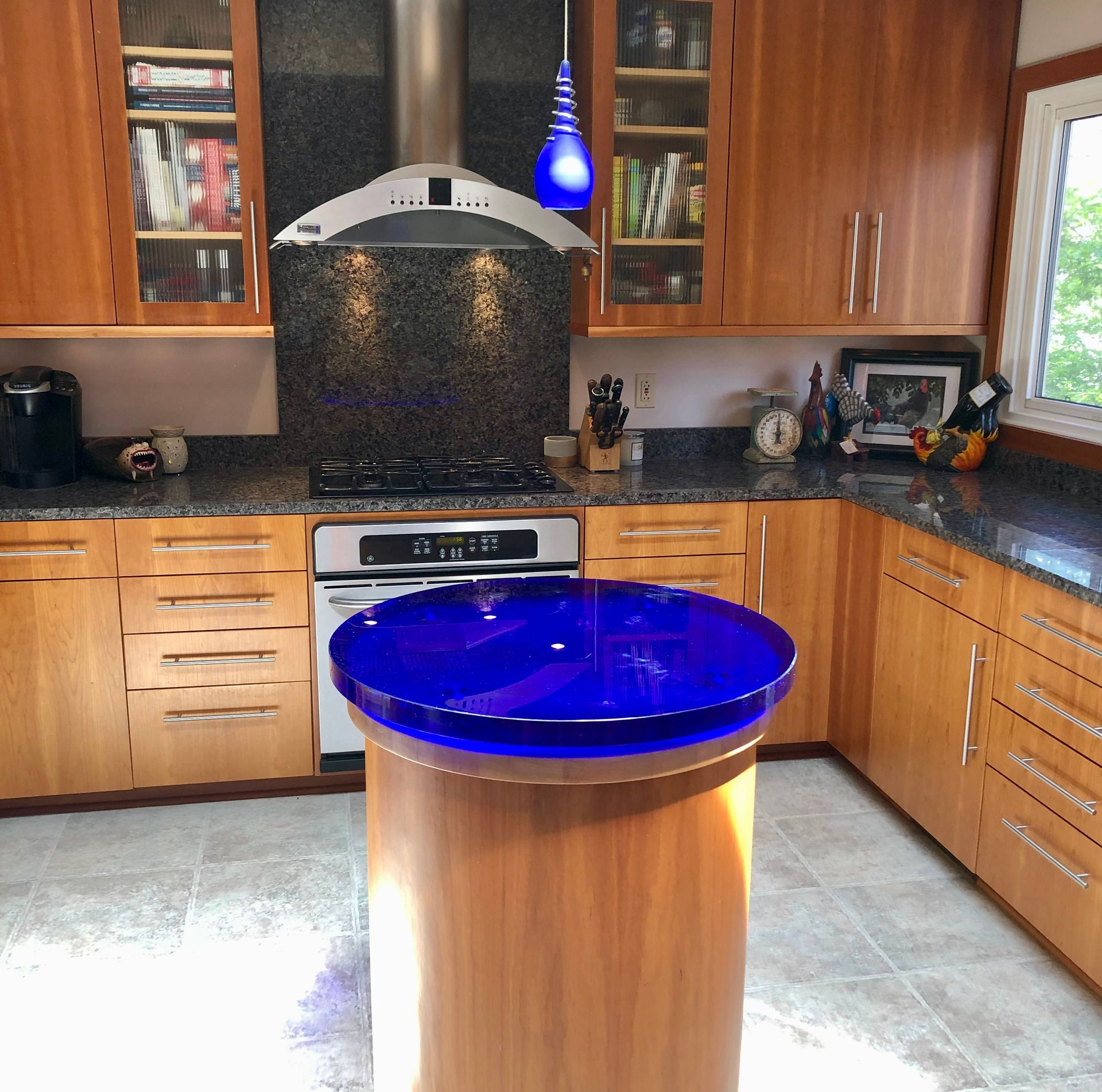 Kitchen with wooden cabinets, granite countertops, and a blue glass island.