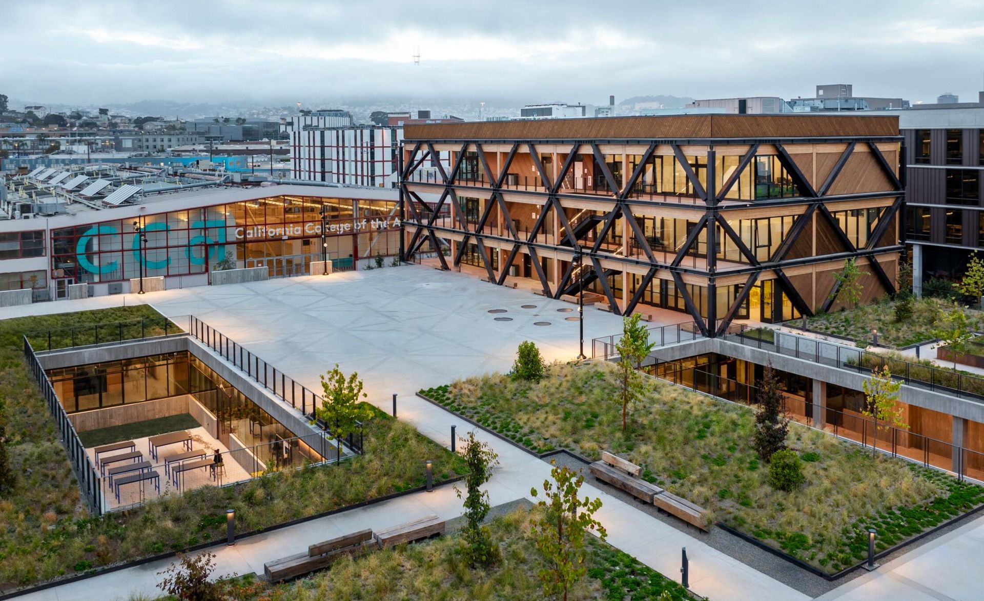 Modern building with a geometric wooden facade and rooftop gardens with glass floor circles in an urban setting.