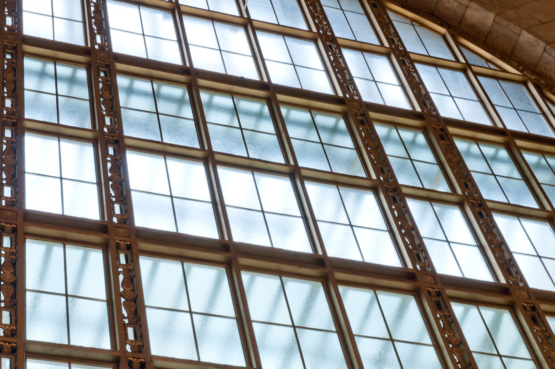 Glass building facade with large grid windows and dark metal beams reflected in the panes