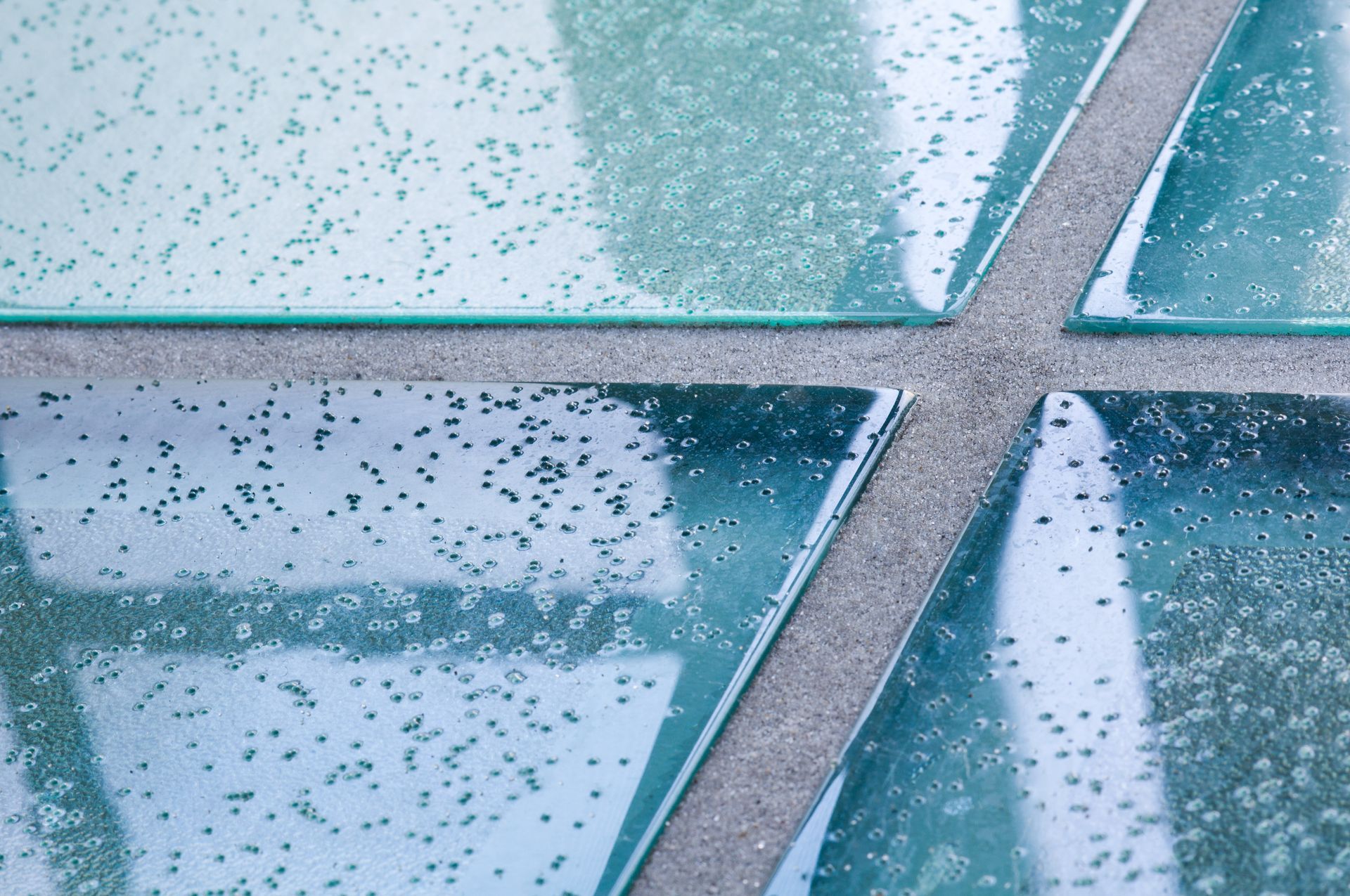Raindrops on frosted blue glass panels with silver metal dividers