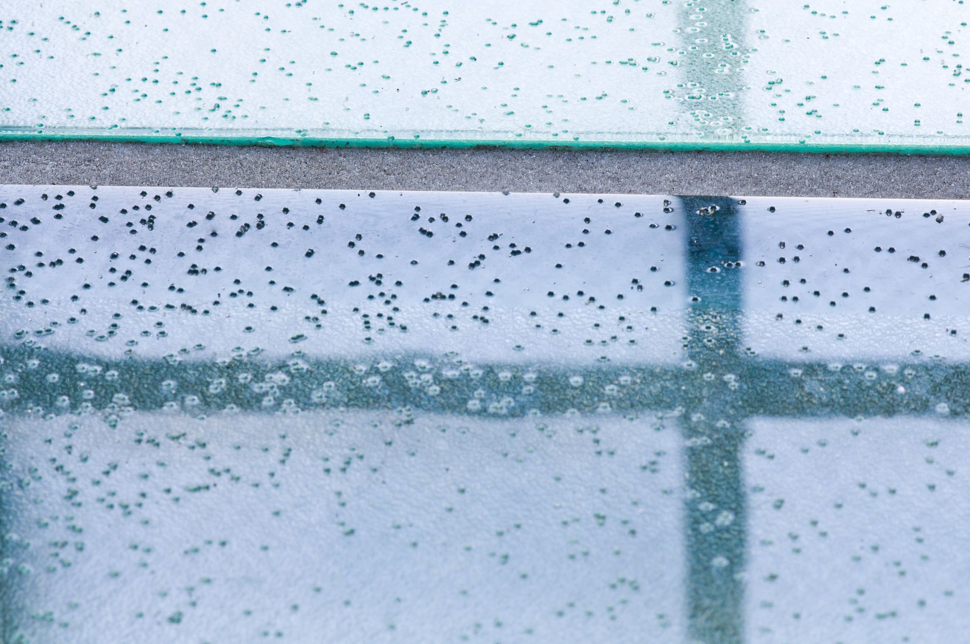 Rain-speckled glass with a blurred window frame and blue-tinted background