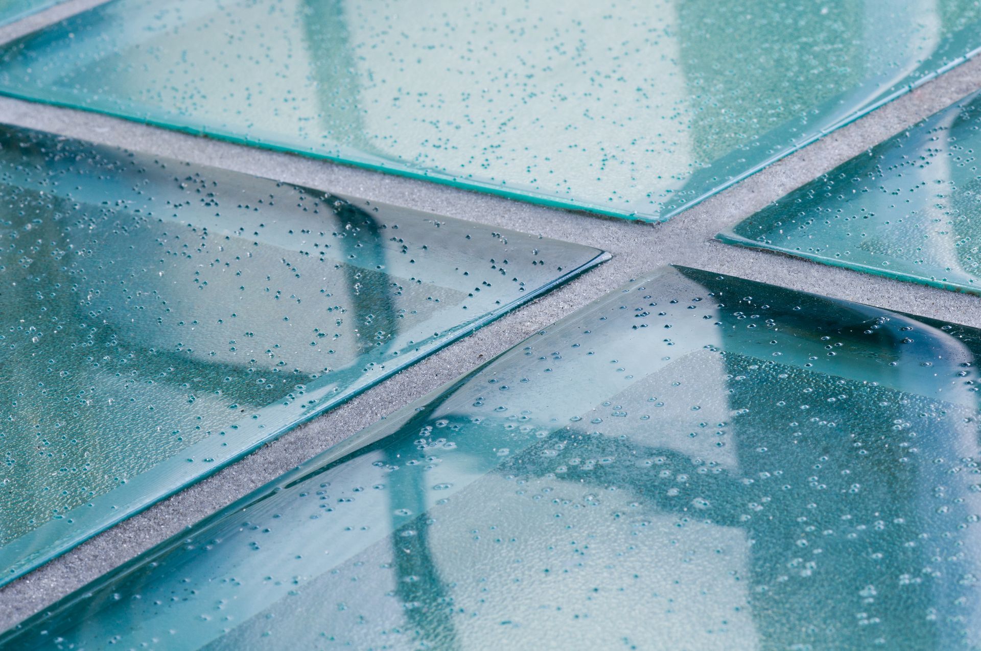 Rain-speckled blue glass panels with intersecting metal frames