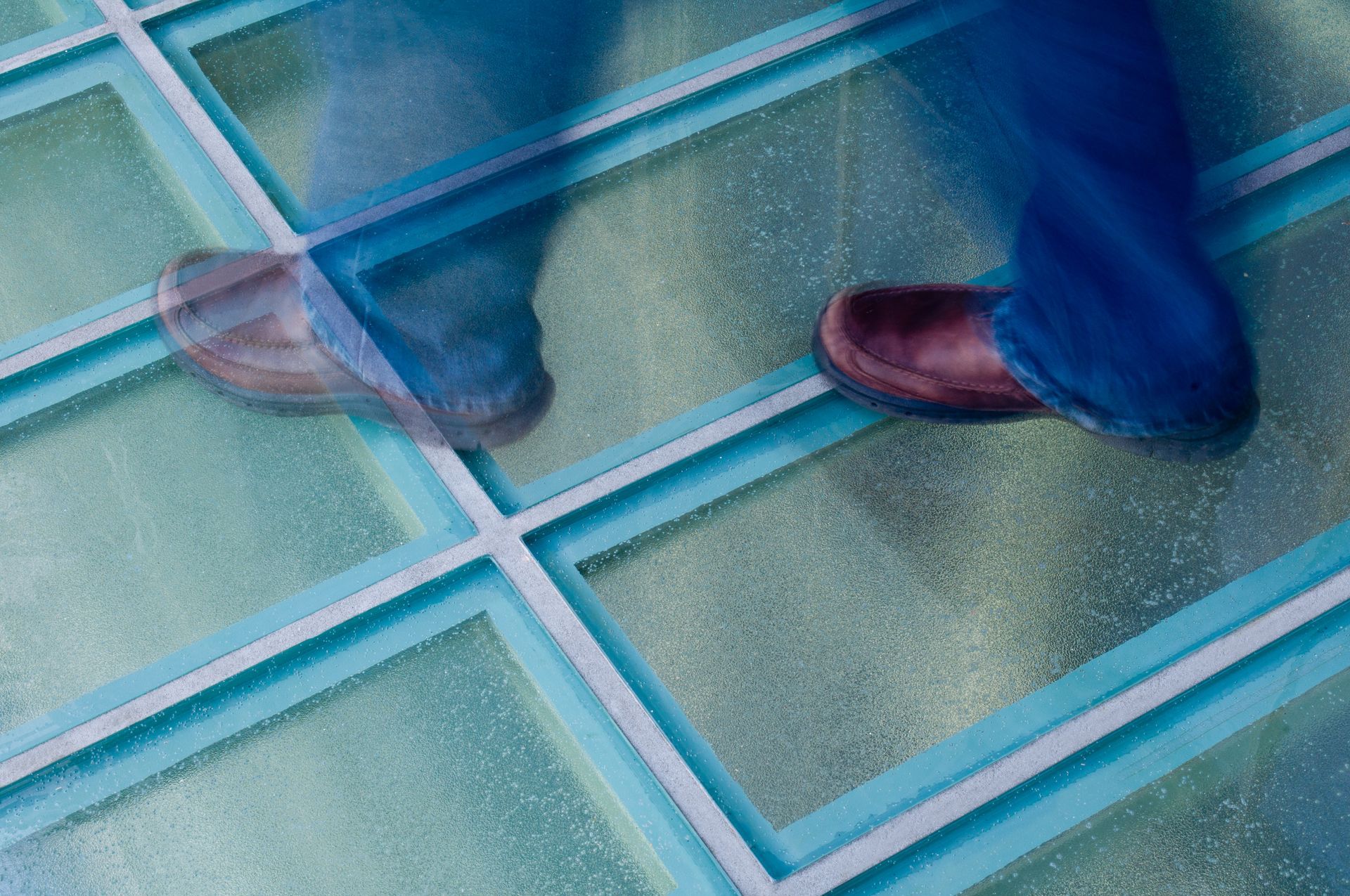 Blue and pink jellyfish gliding over a turquoise tiled pool floor