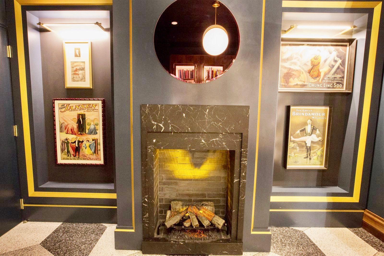 Fireplace with framed art and a circular mirror. Yellow accents frame the dark gray wall and the fireplace.
