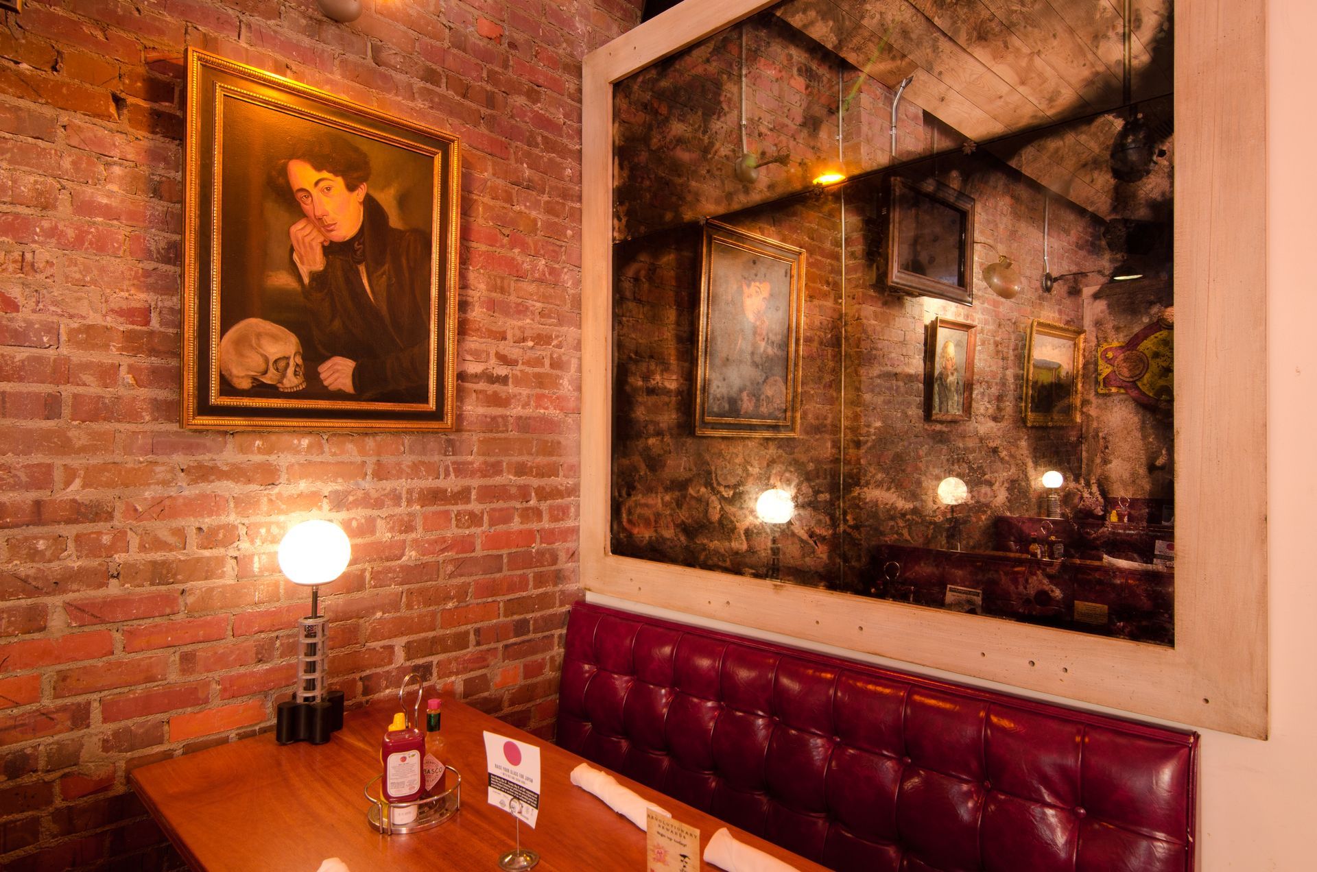 A dining room with a brick wall and a antique mirror on the wall.