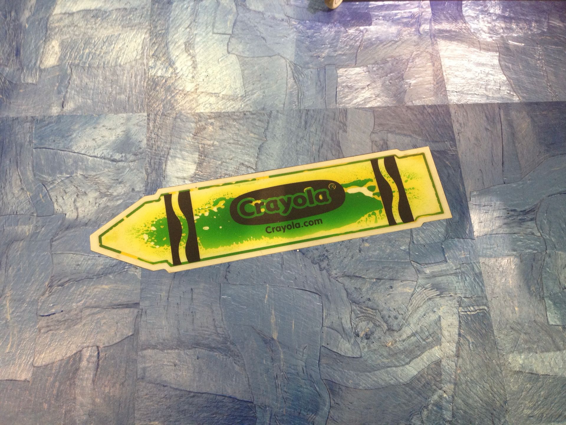 A yellow and green crayola crayon on the floor