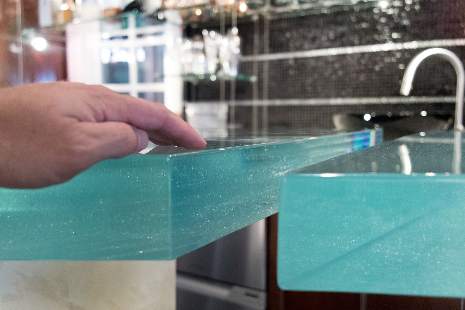 A hand resting on a thick glass countertop A hand resting on a thick glass countertop