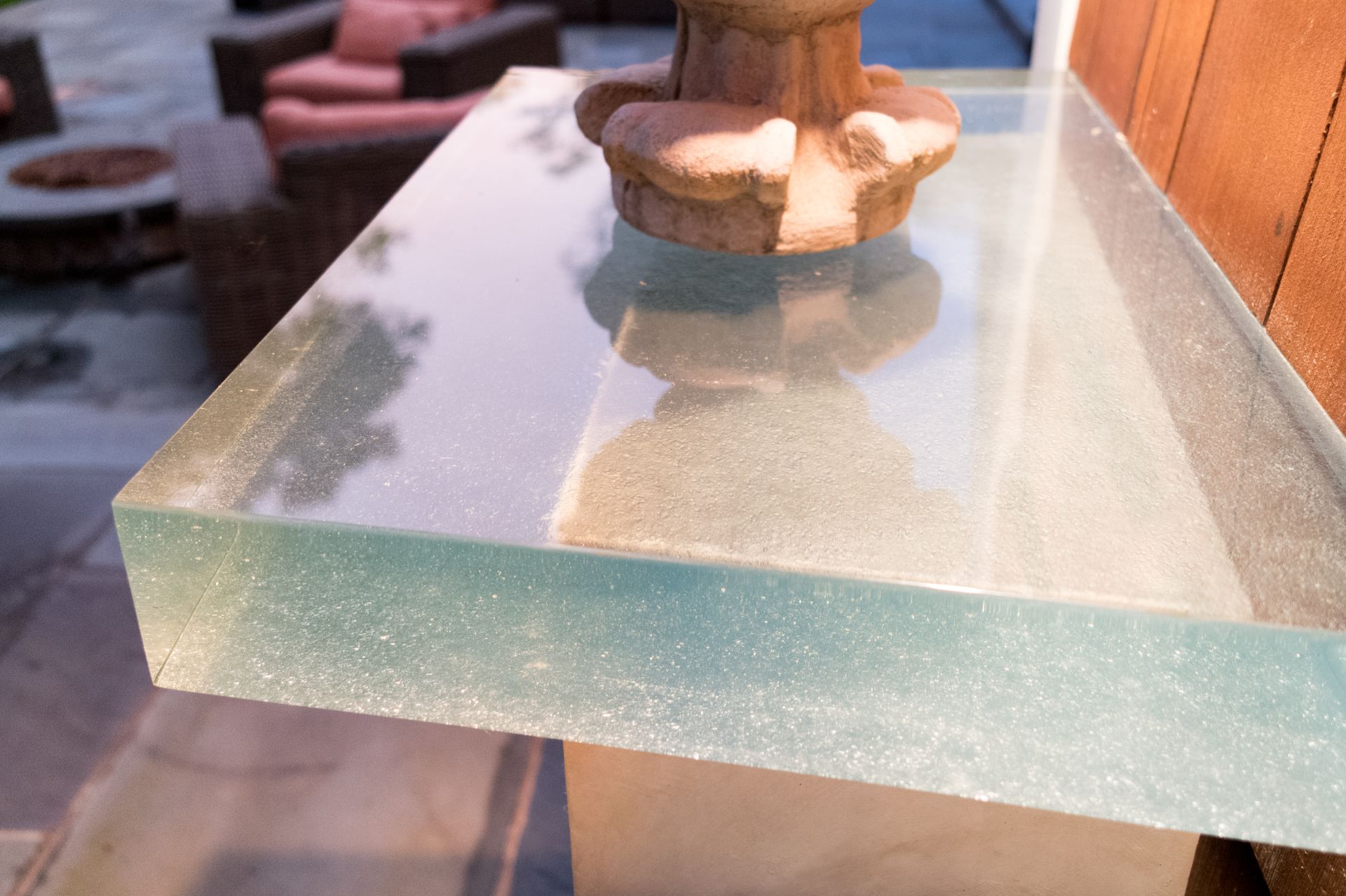 Clear glass tabletop with a stone planter and sunlight reflections outdoors