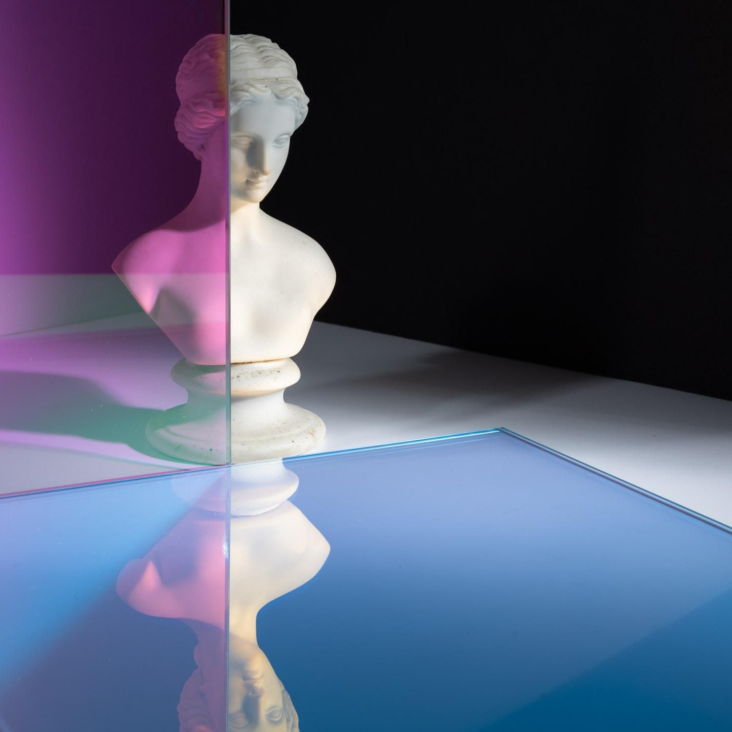 A bust reflecting on a piece of dichroic glass on the ground.