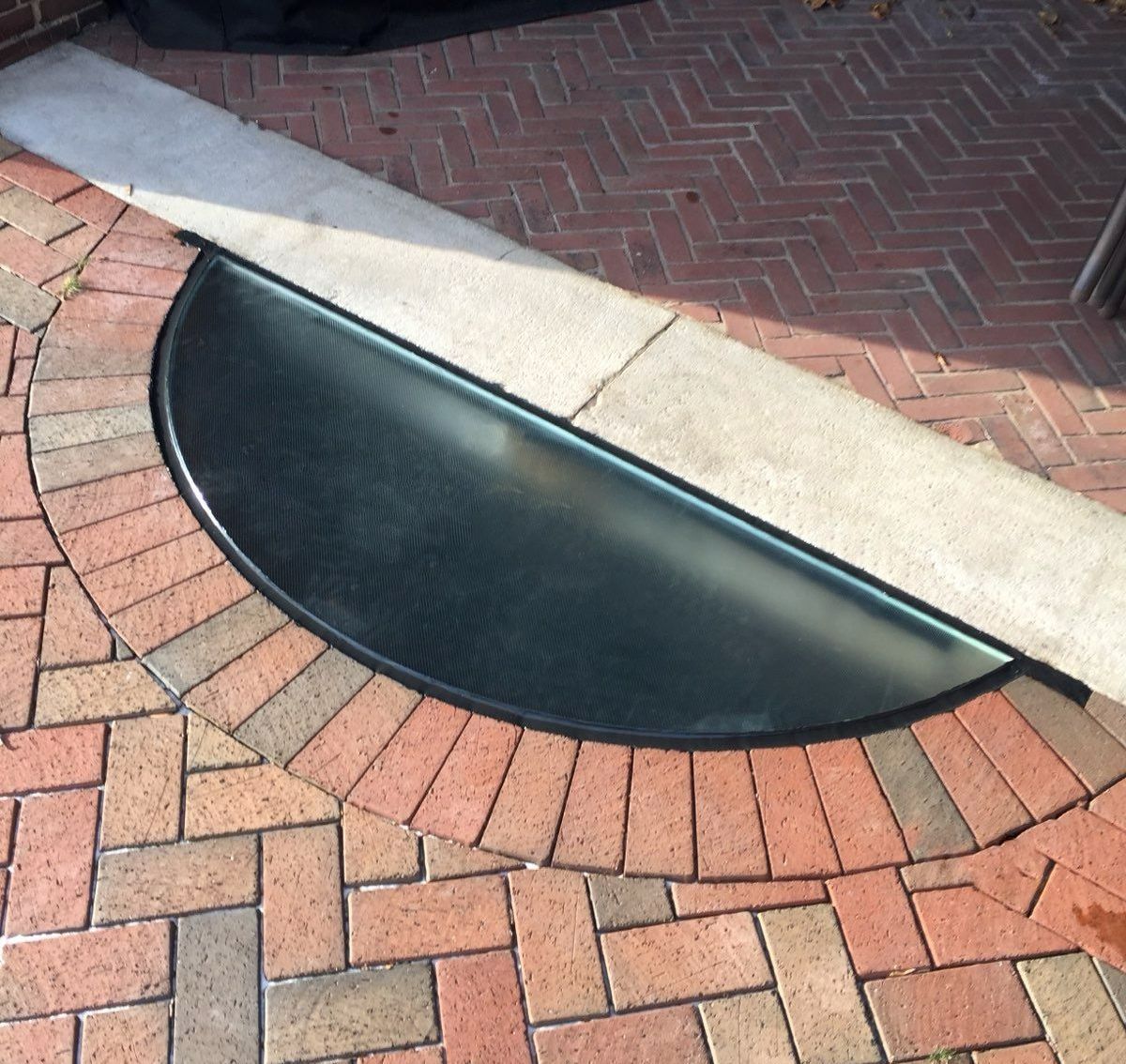 A half circle walkable glass skylight on a brick floor
