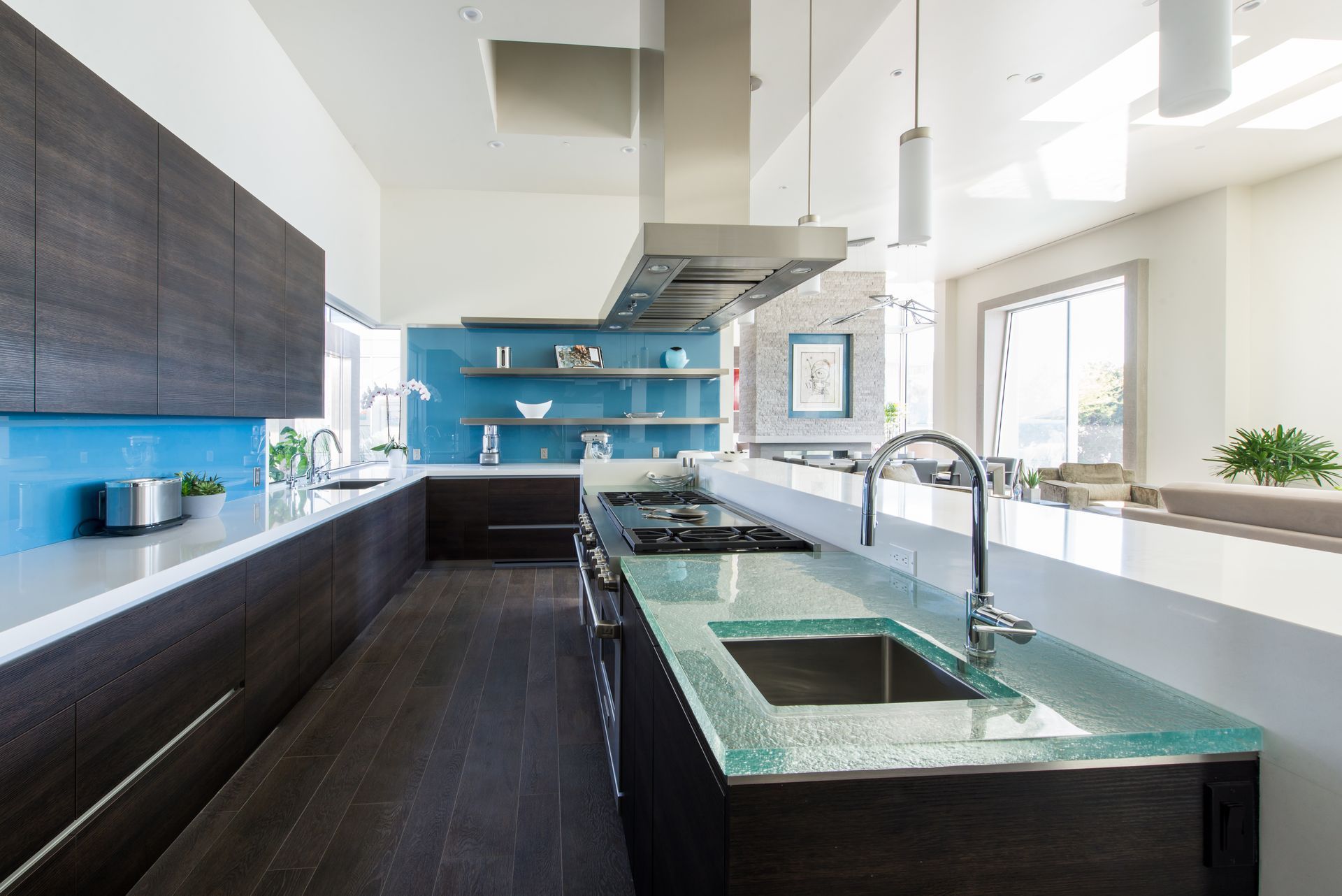 A kitchen with a long glass counter top and a sink.