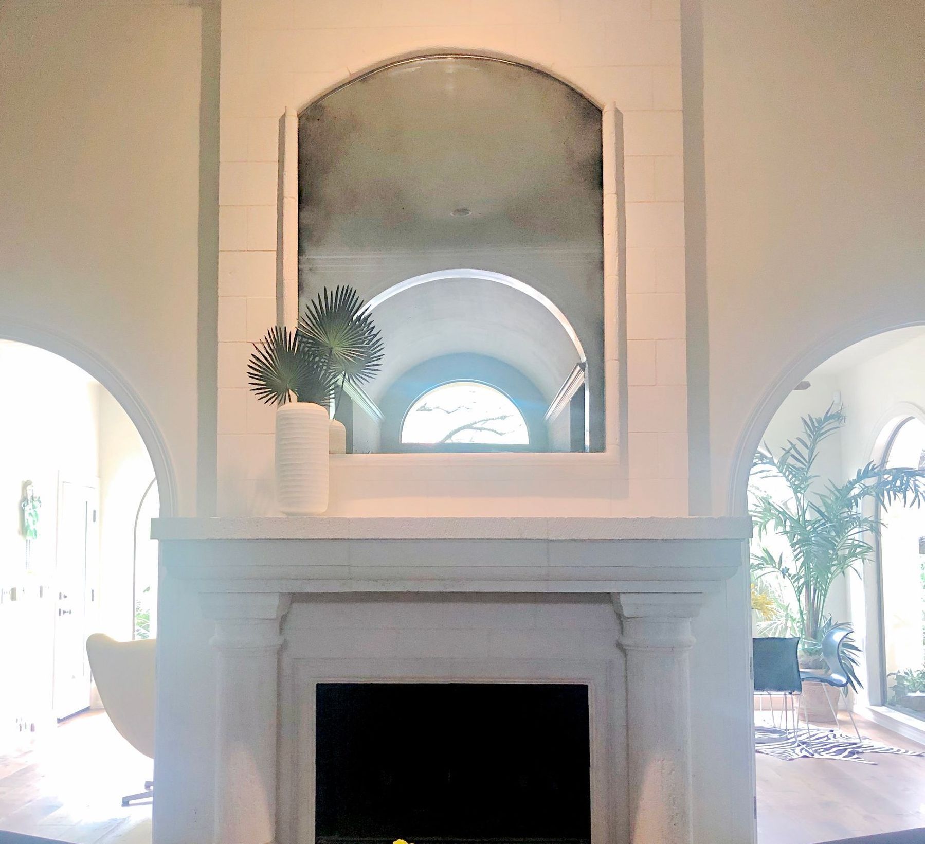 A fireplace with a framed antique mirror above it in a living room