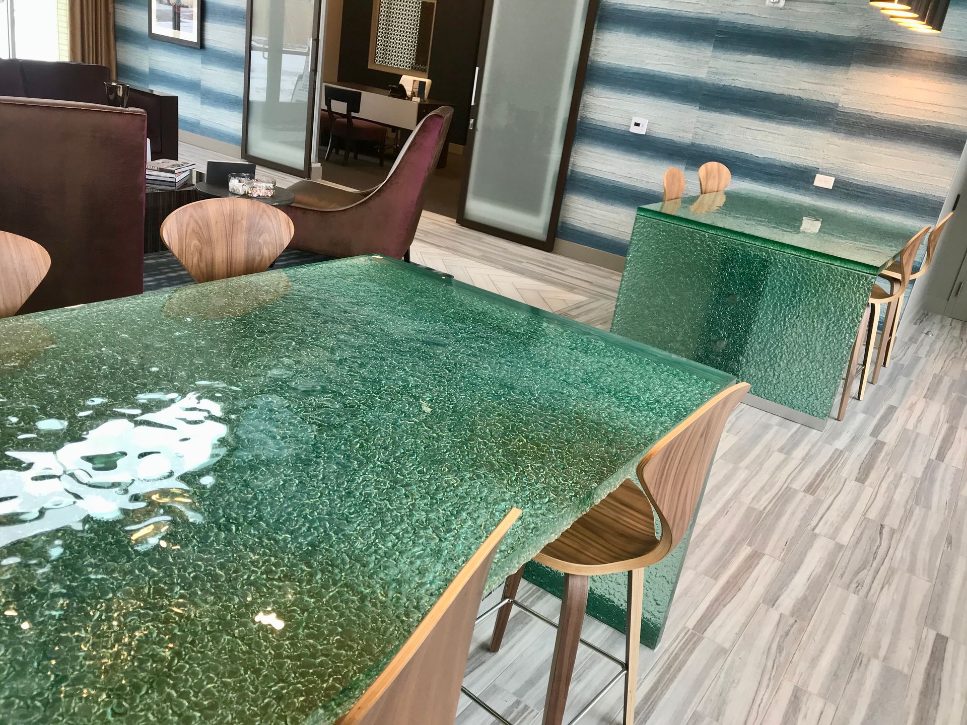 Green-topped tables and stools in a small café or dining area with striped walls