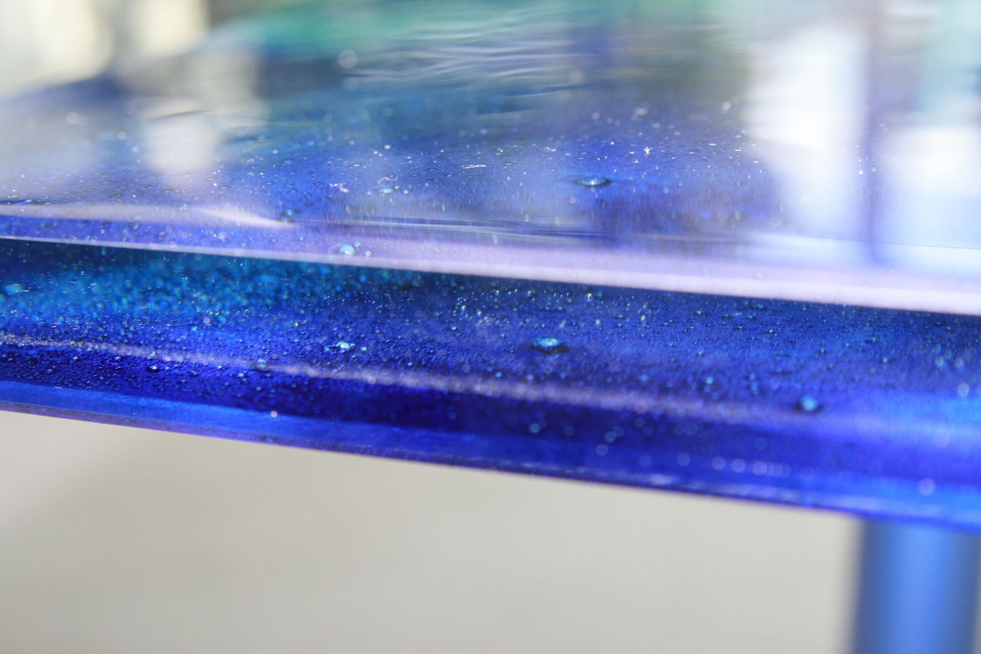 Blue glass shelf with water droplets on a blurred indoor background