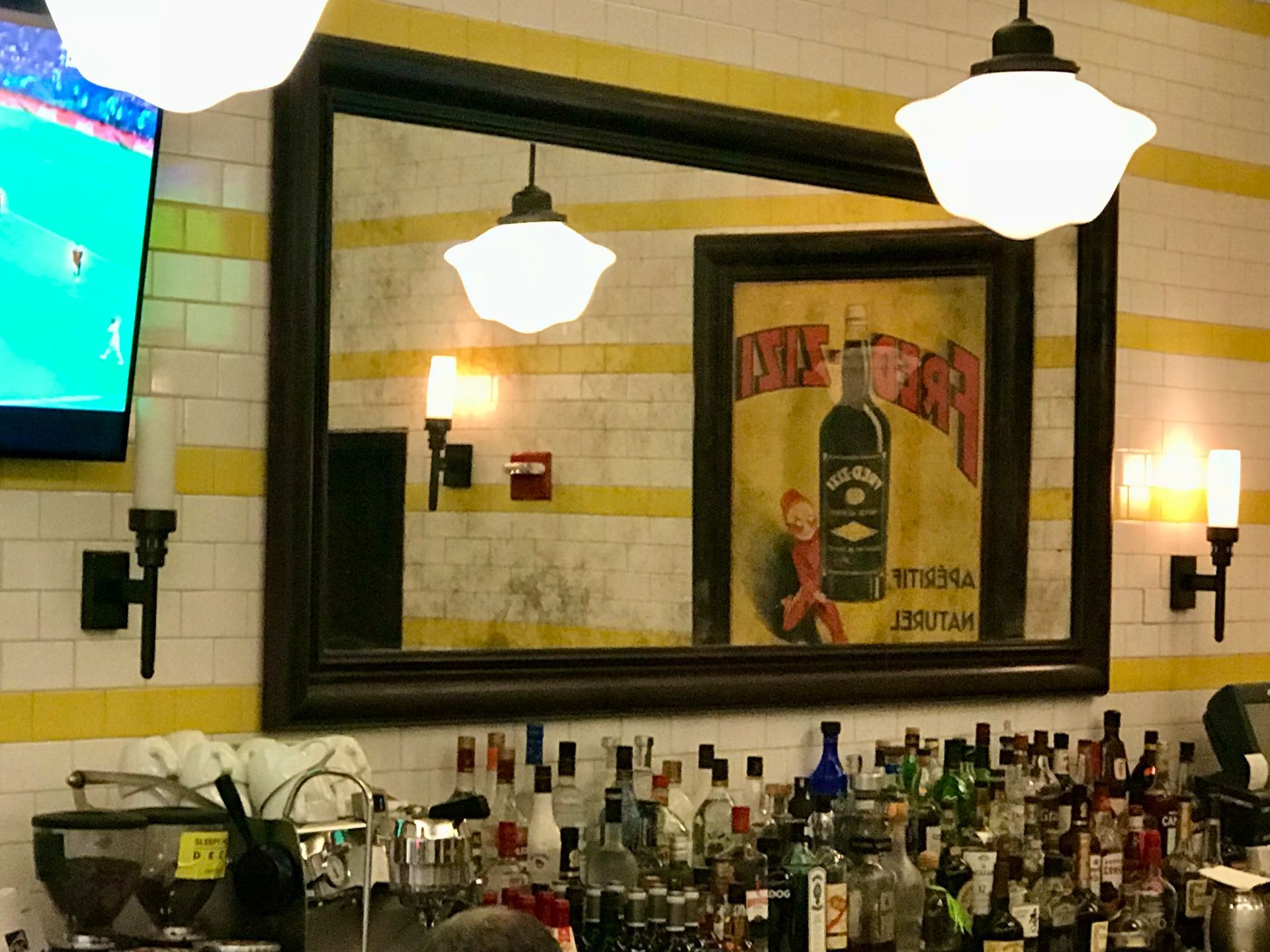 A large framed antique mirror with a picture of a bottle on it