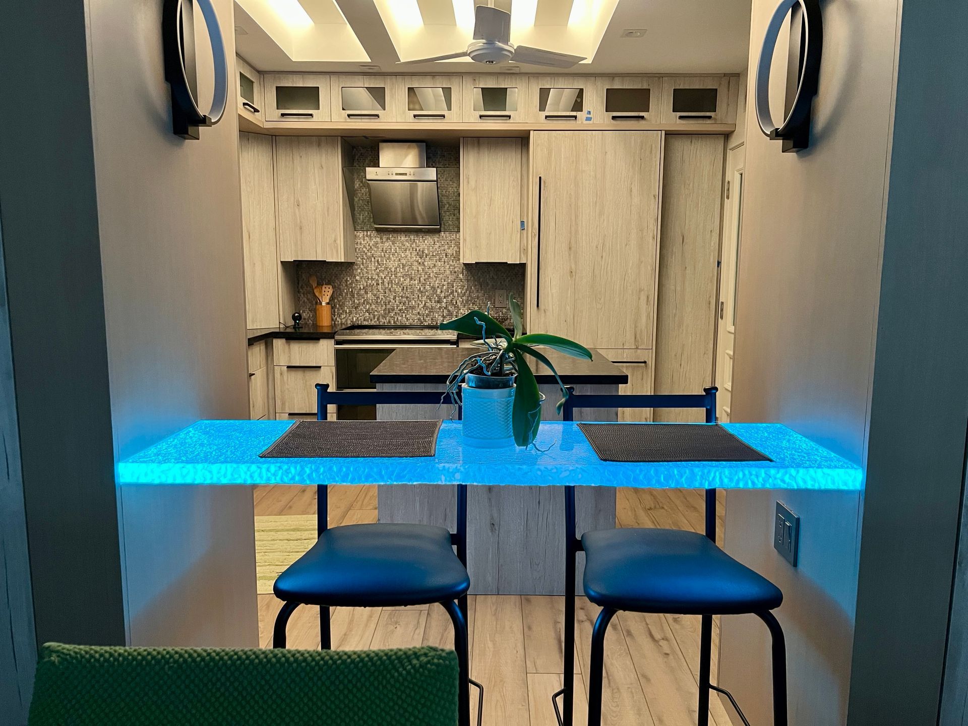 A kitchen with a glass table top and chairs and a plant on it
