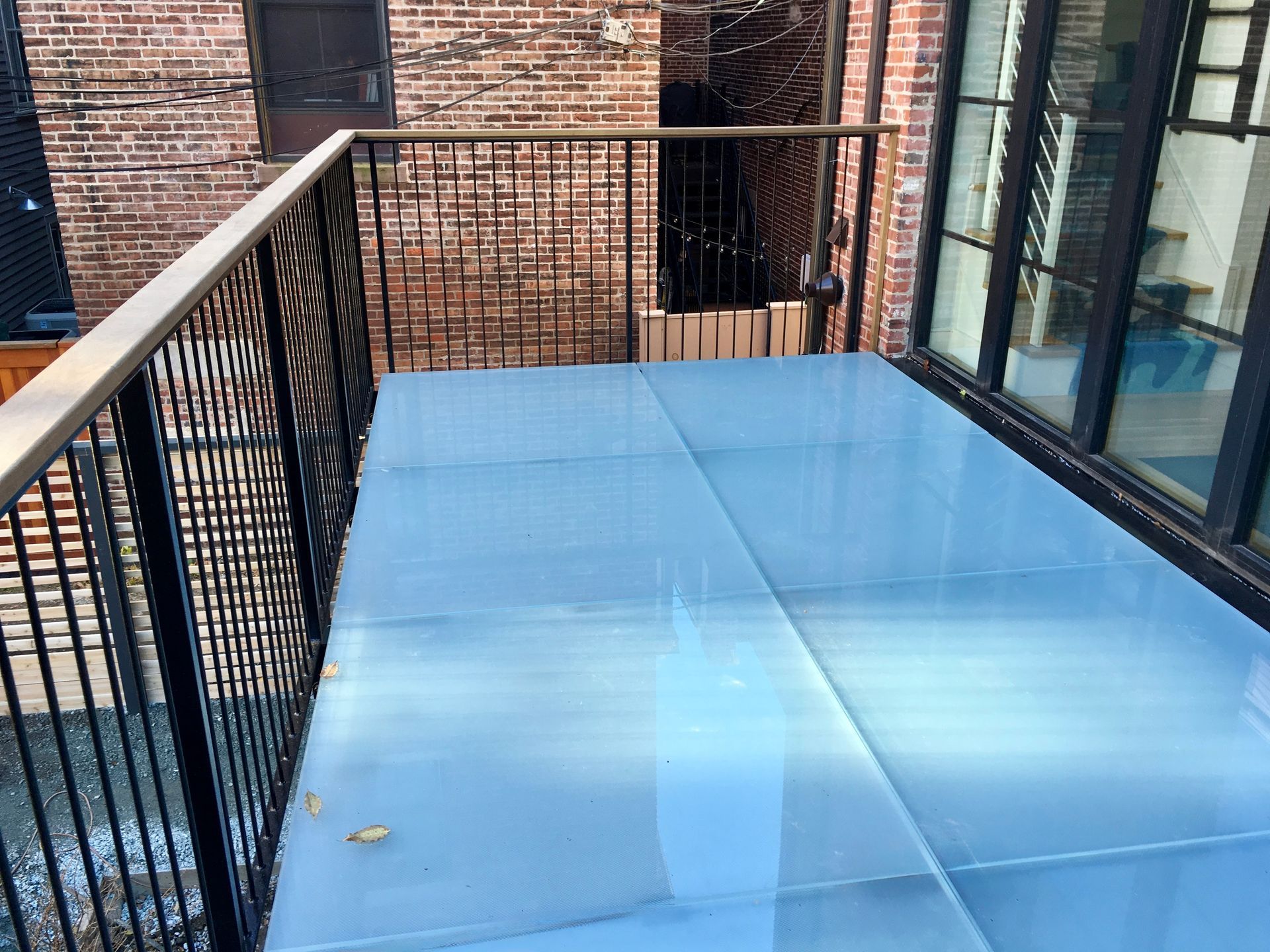 Blue tarp-covered balcony with black metal railing beside a brick building