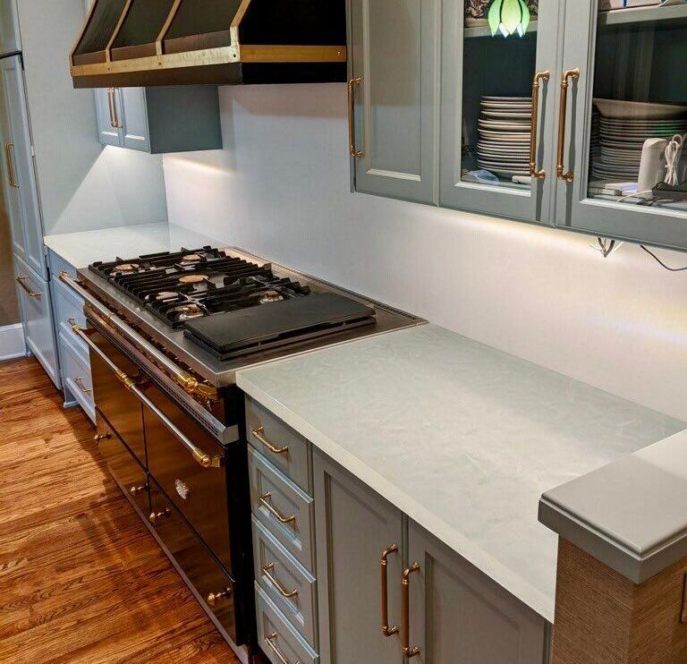 A kitchen with a stove top oven, glass counter top and cabinets