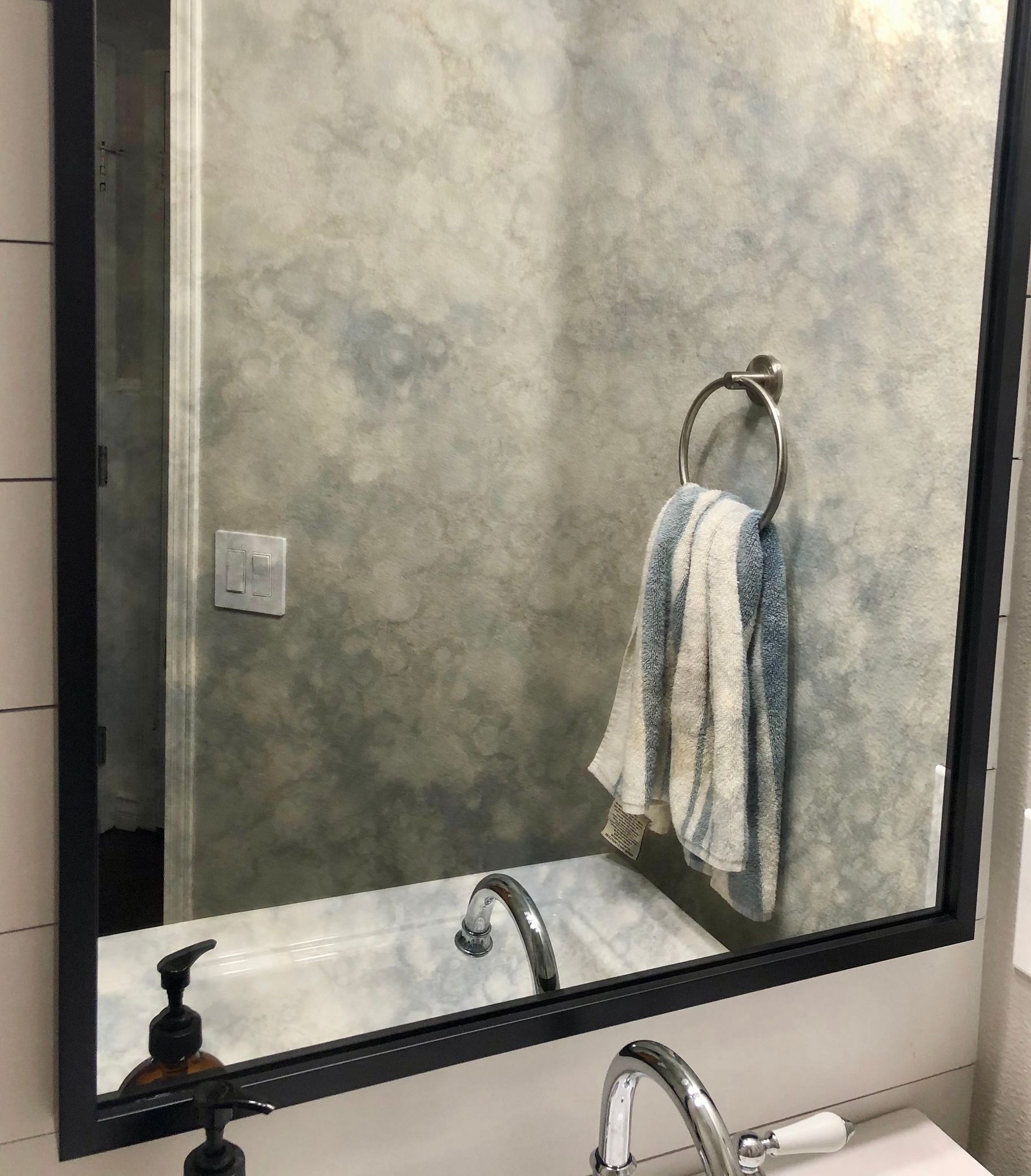 A bathroom mirror with a towel hanging on it