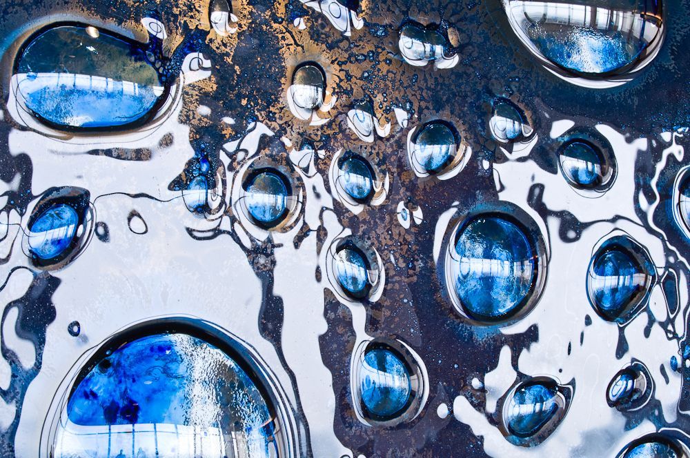 Blue water droplets on a glossy, abstract surface with metallic reflections