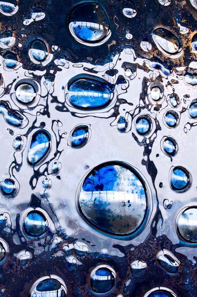 Blue and clear water droplets on a reflective dark surface