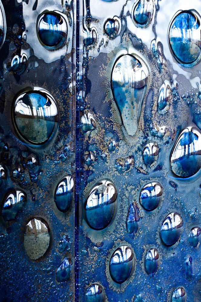 Blue water droplets on a reflective, textured surface