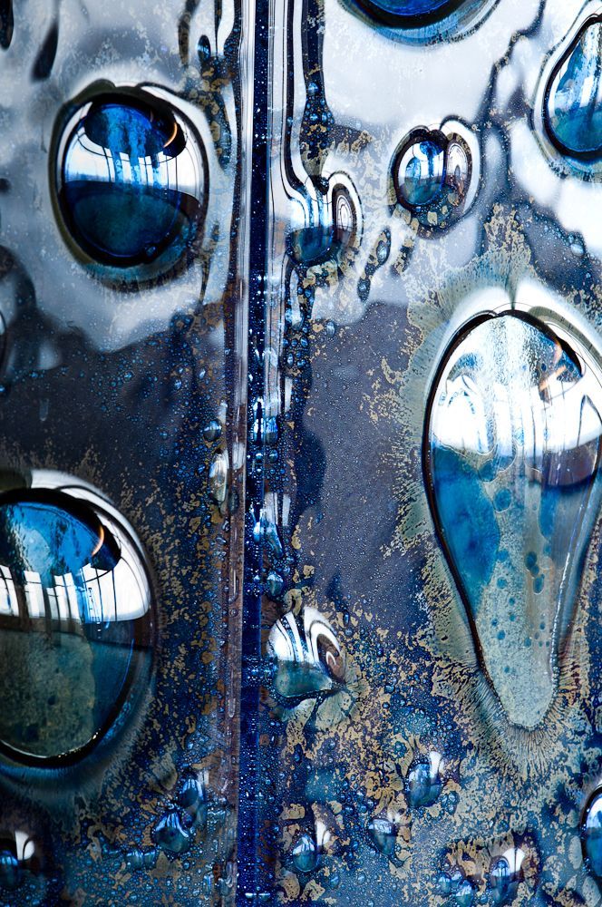 Abstract blue and silver water droplets and bubbles on a textured metallic surface