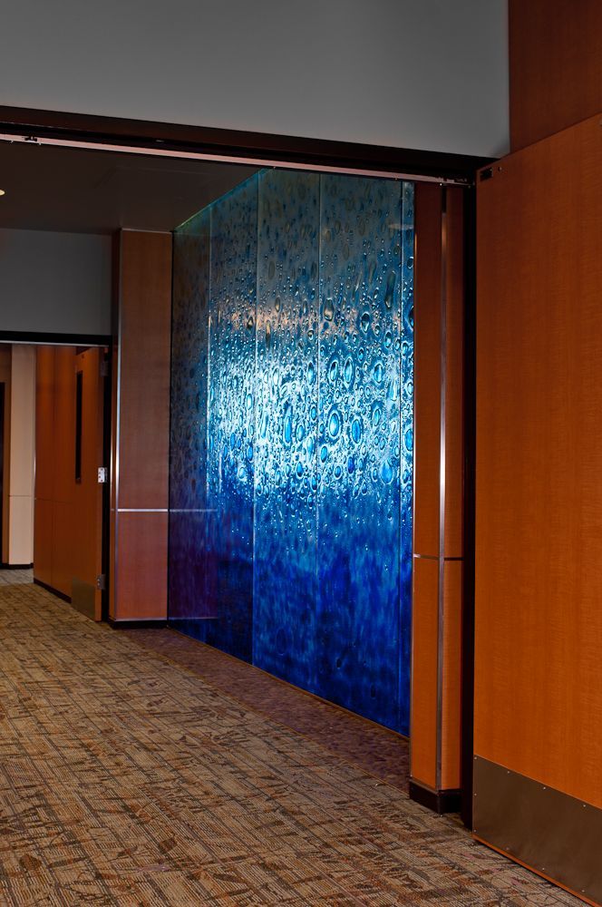 Hallway with a large blue textured wall panel and carpeted floor inside a building