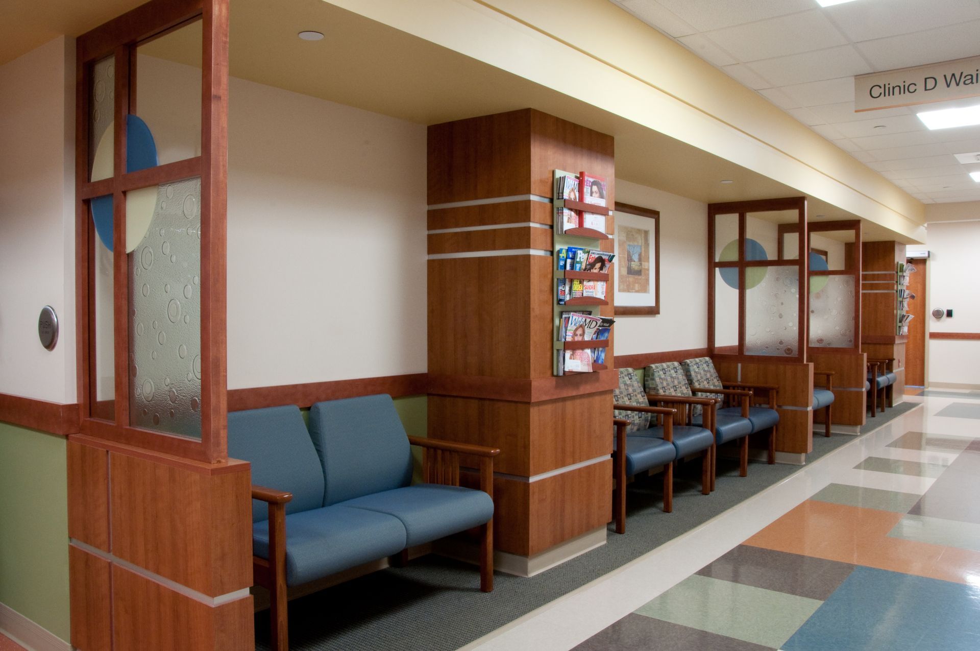 Empty hospital waiting area with blue chairs and wood-paneled walls