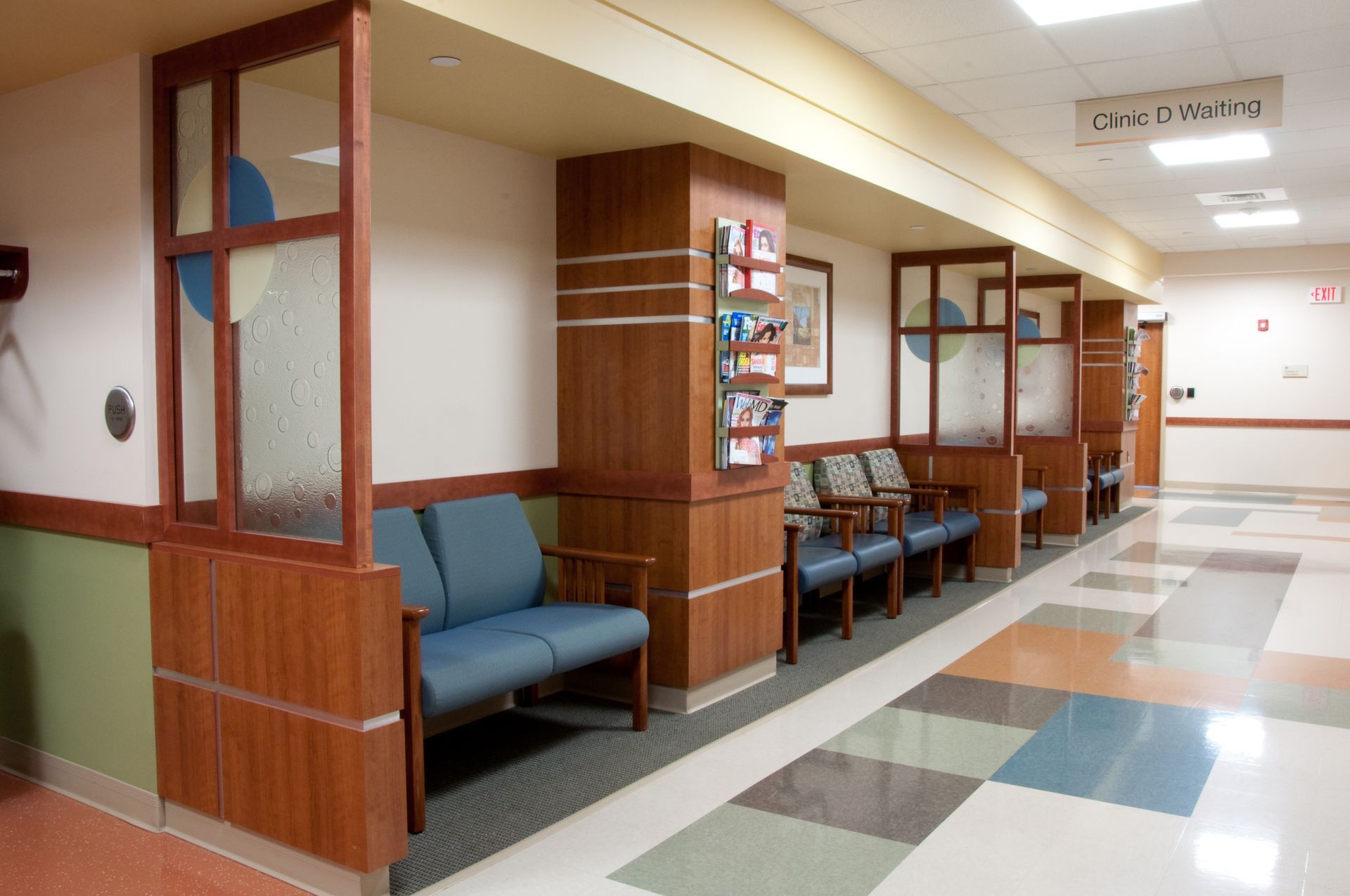 Empty hospital waiting area with blue chairs, wood-paneled walls, and tiled floor