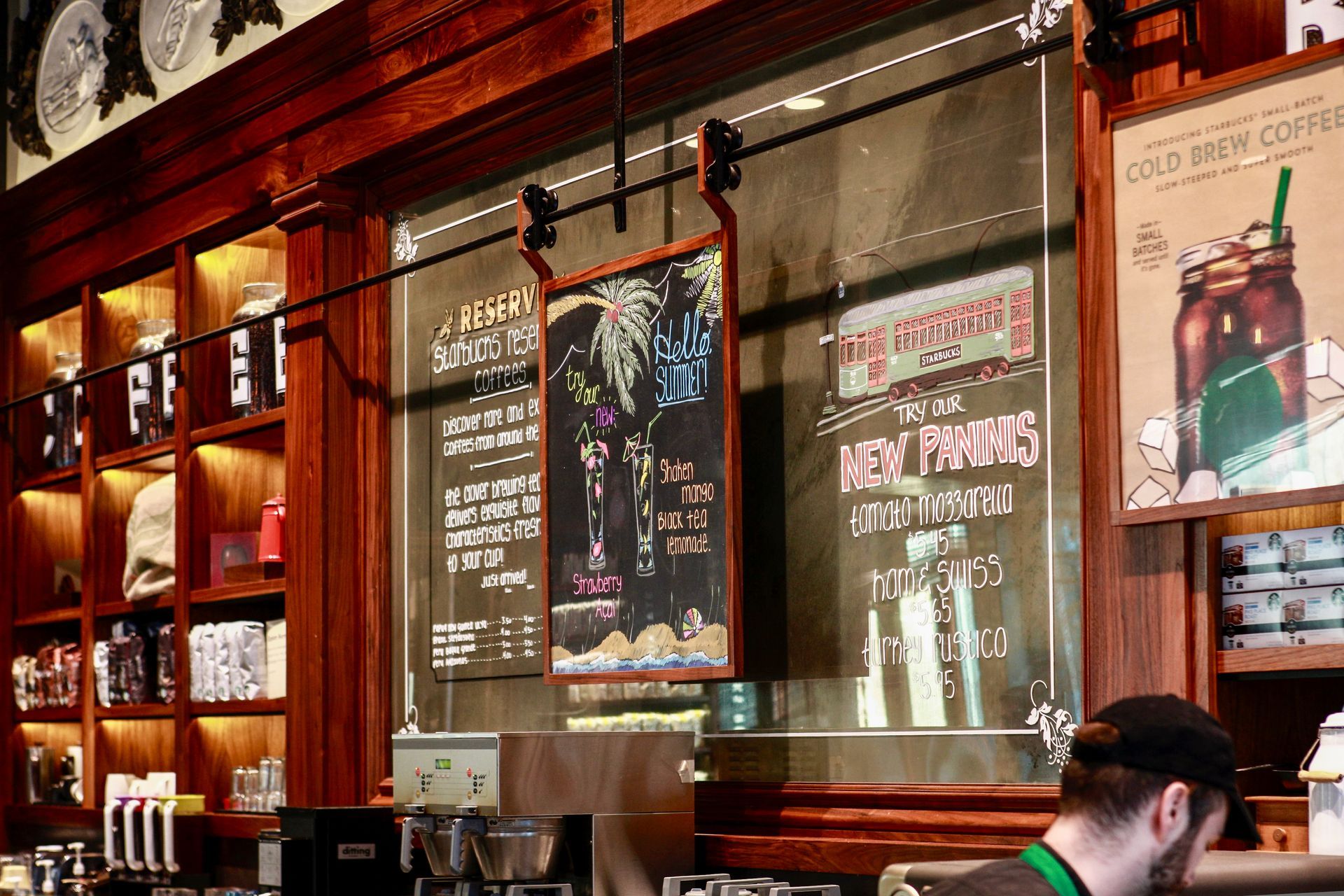 A man is standing behind a counter in a starbucks coffee shop.