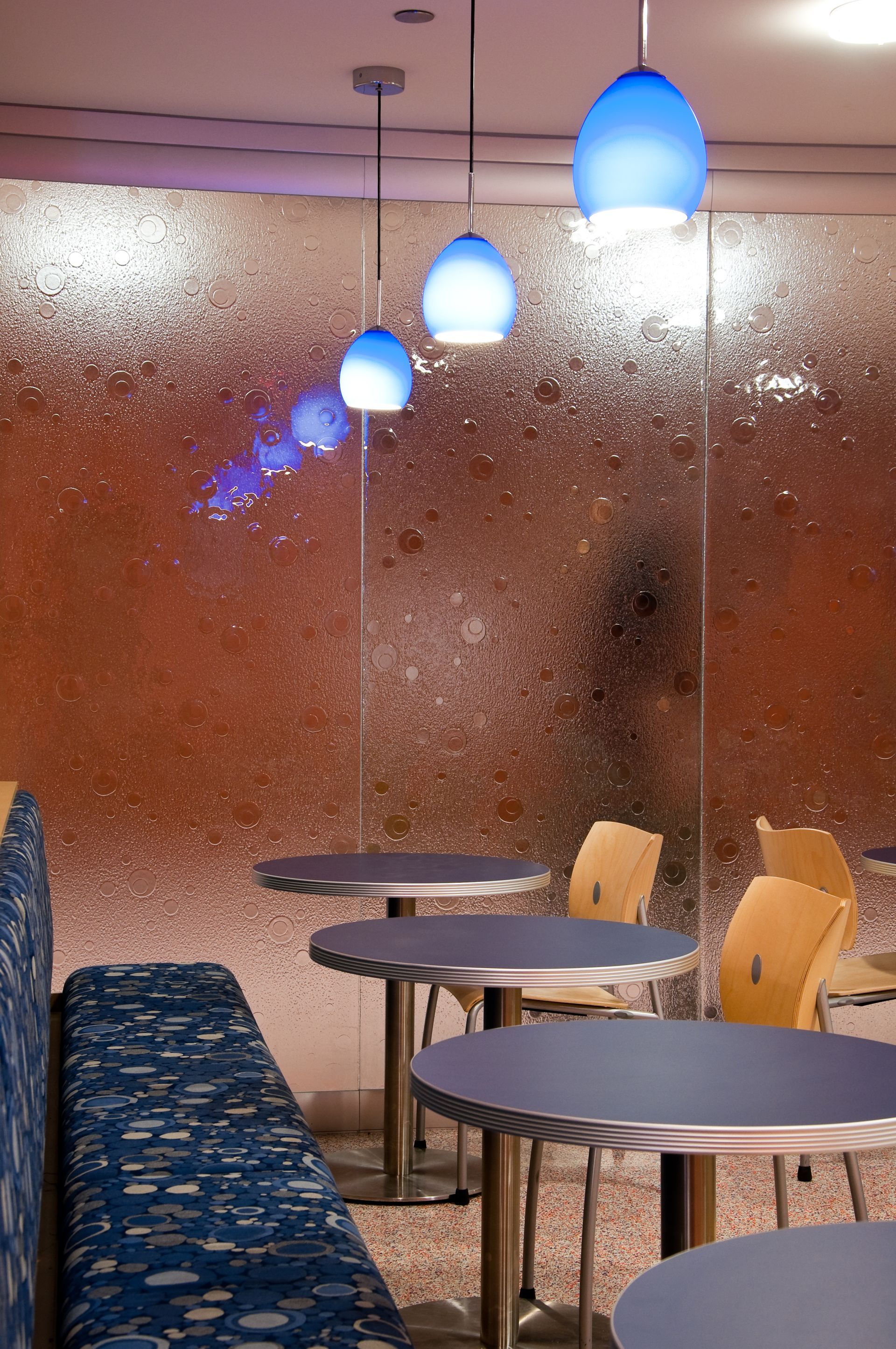 Small café seating area with blue pendant lights and a frosted glass partition.
