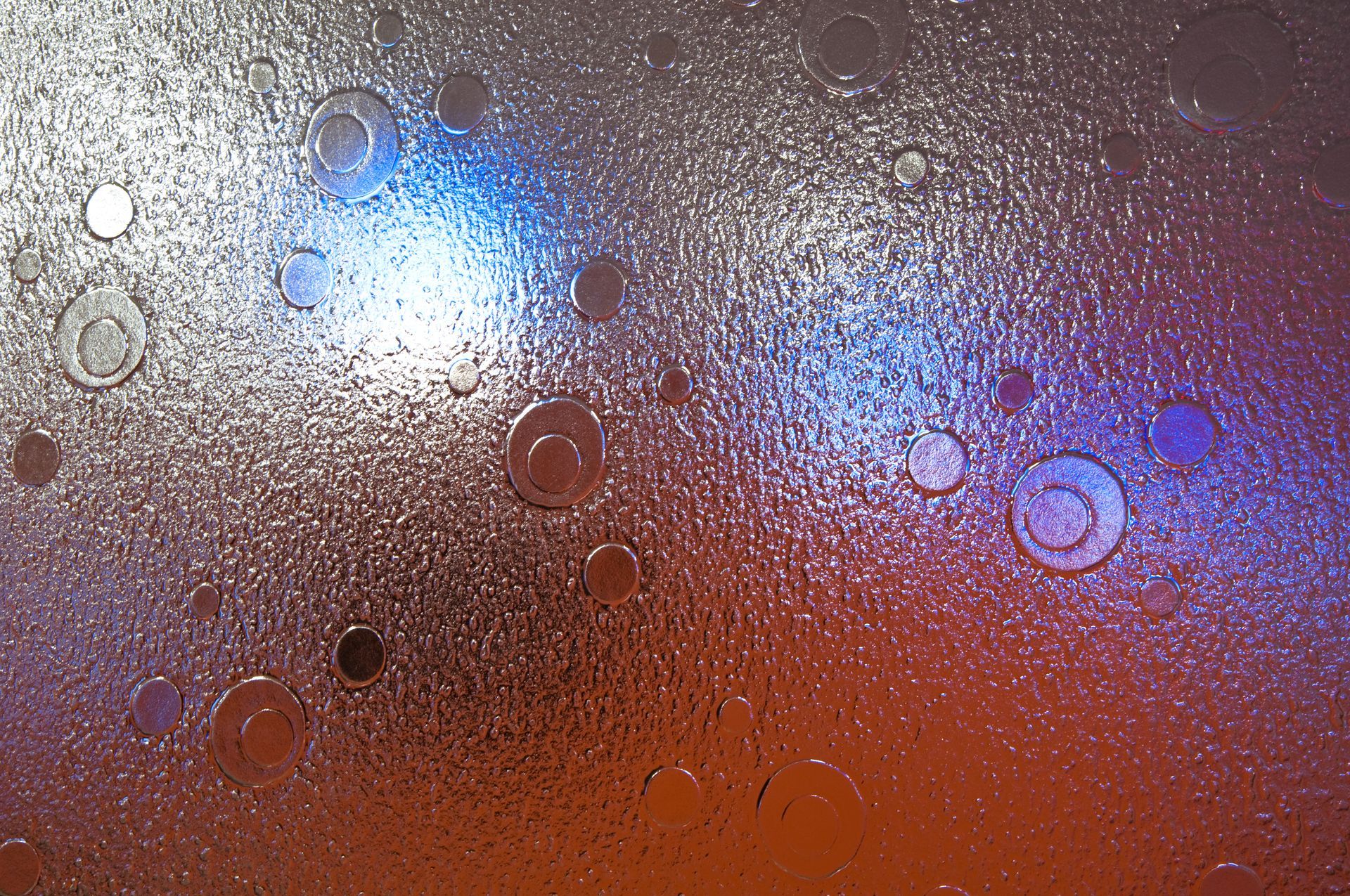 Abstract frosted glass with water droplets and blurred blue, purple, and orange lights