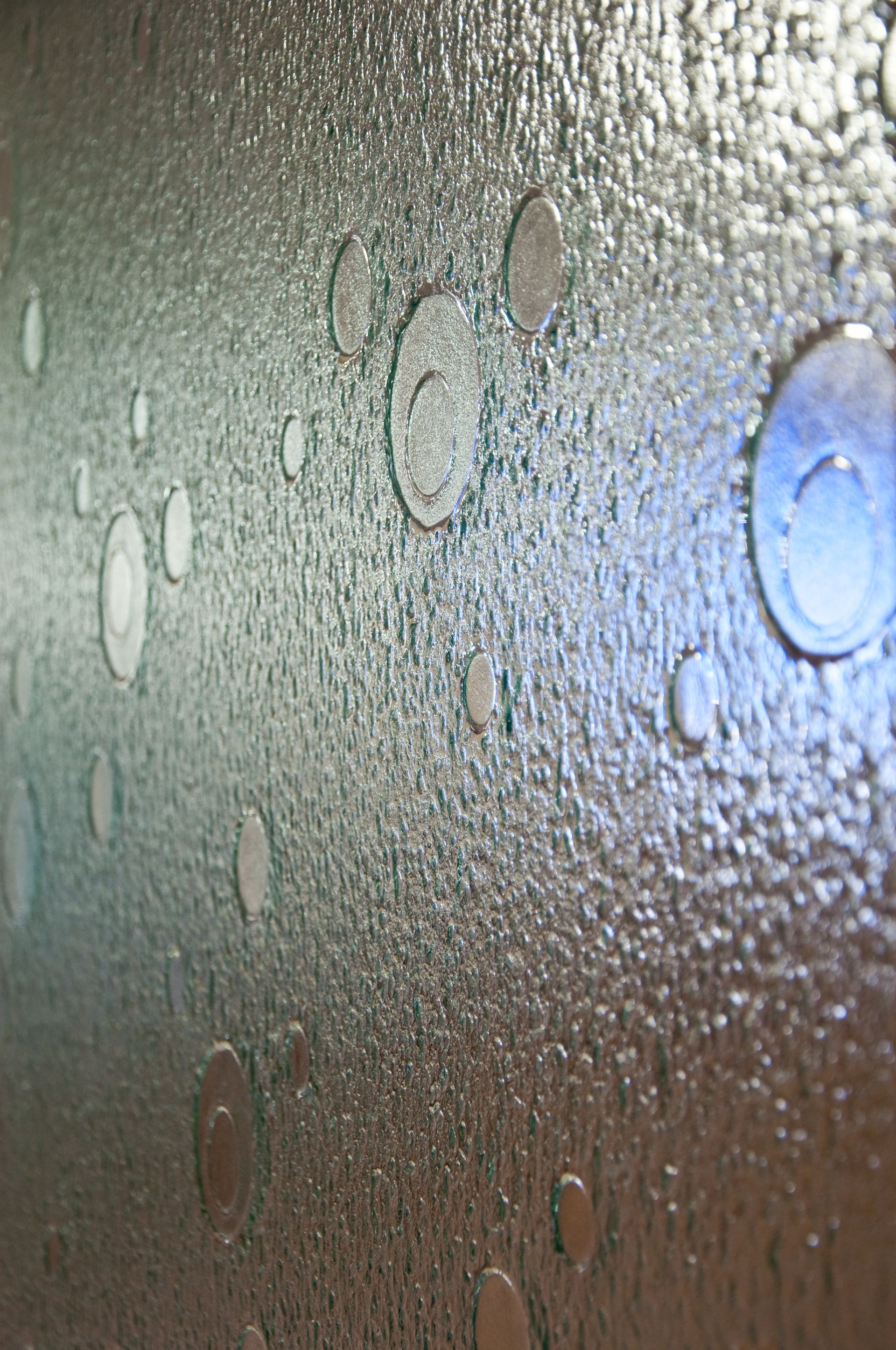 Textured frosted glass with water droplets and a bright blue light reflection on the right