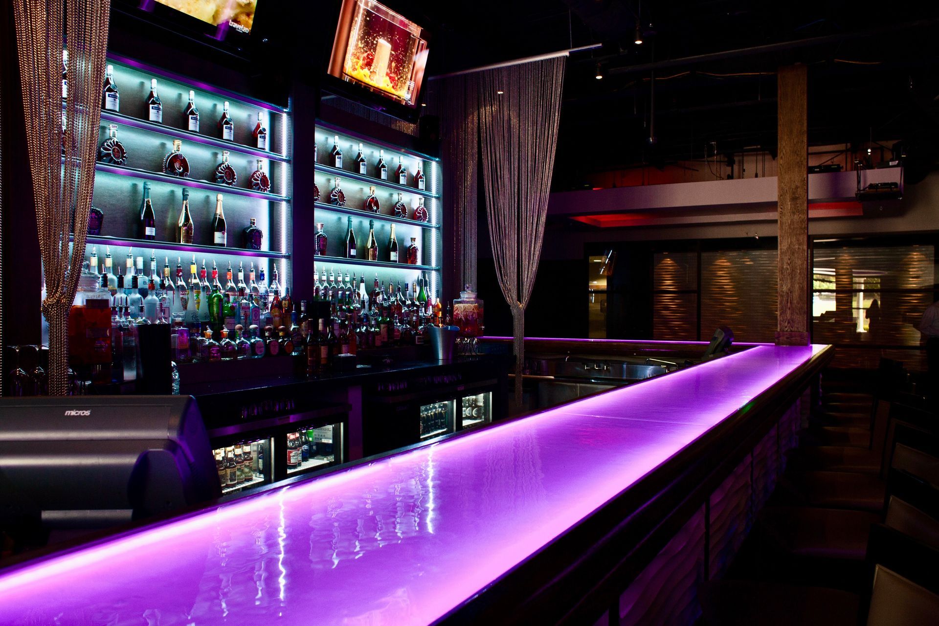A bar with purple lights on the glass counter top