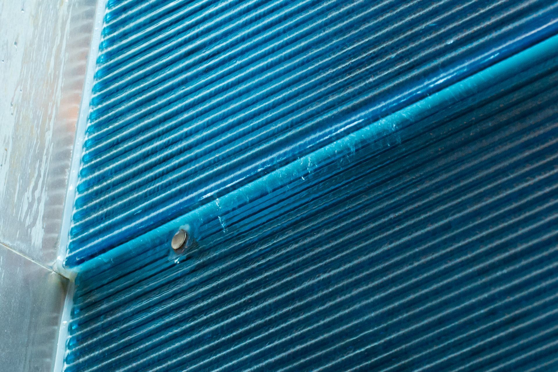 Close-up of blue corrugated plastic panels with a small metal fastener on the edge