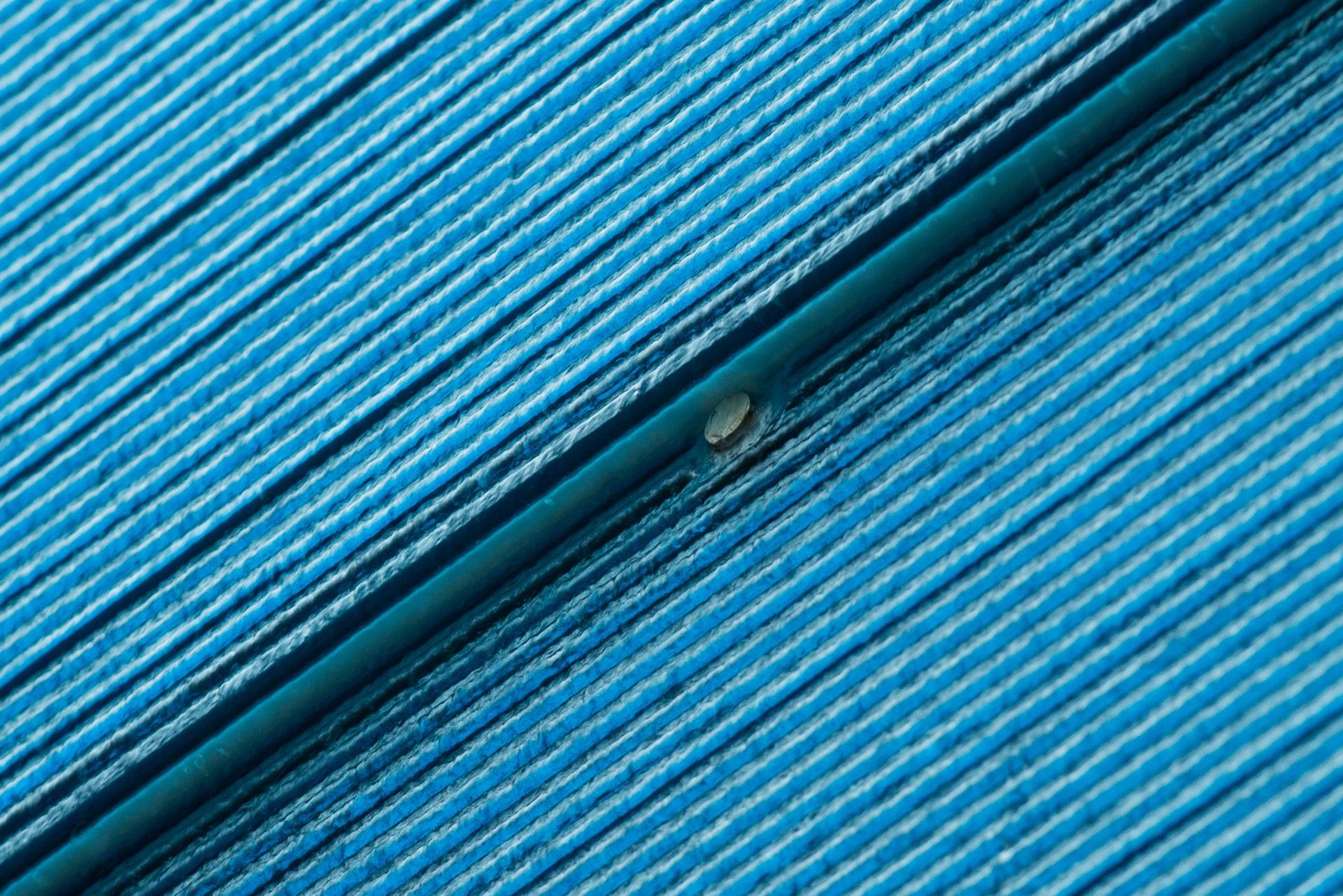 Blue textured surface with diagonal ridges and a small circular opening