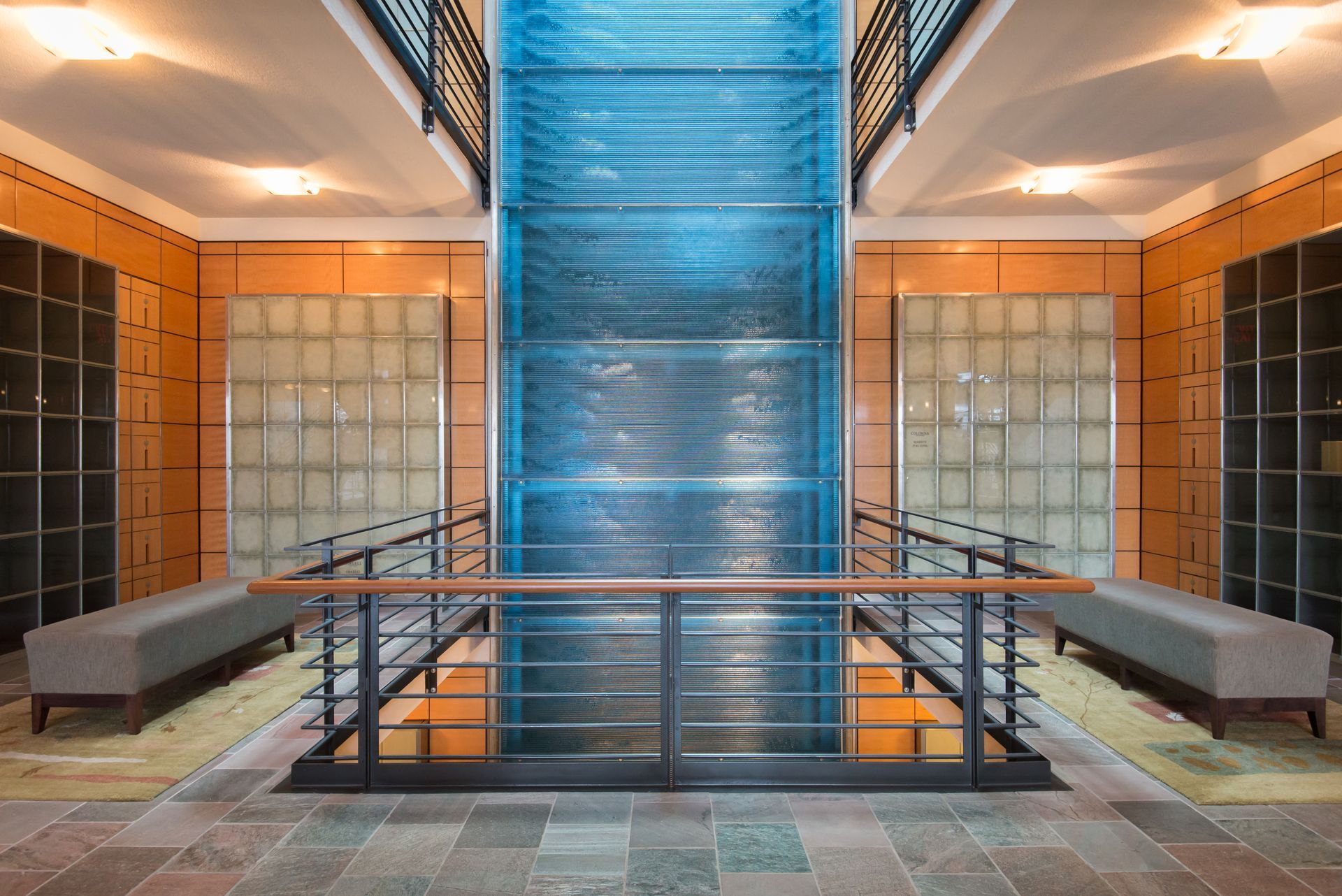 Modern interior with blue central staircase, orange walls, and benches on both sides