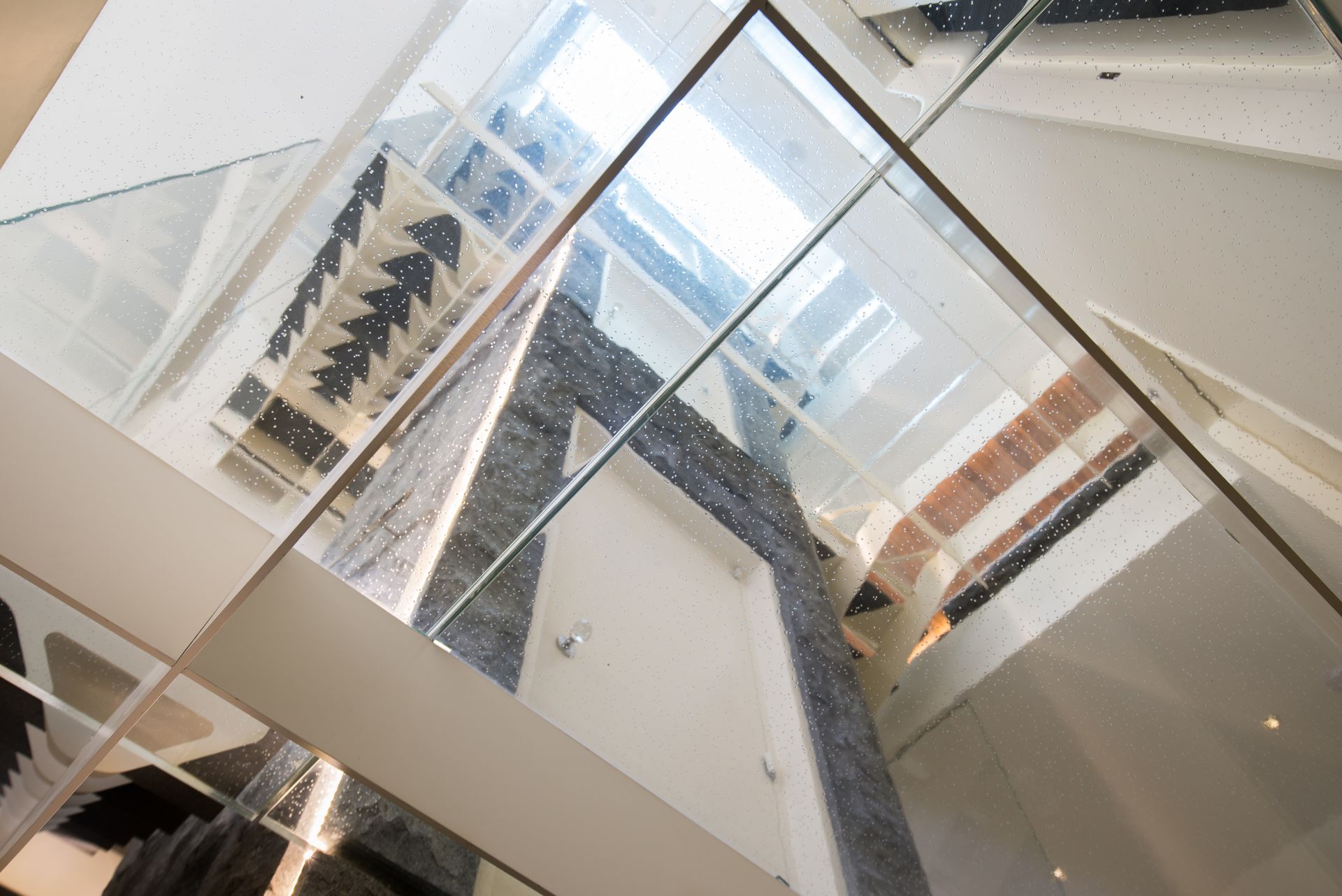 Modern glass atrium with escalators, white walls, and geometric ceiling beams