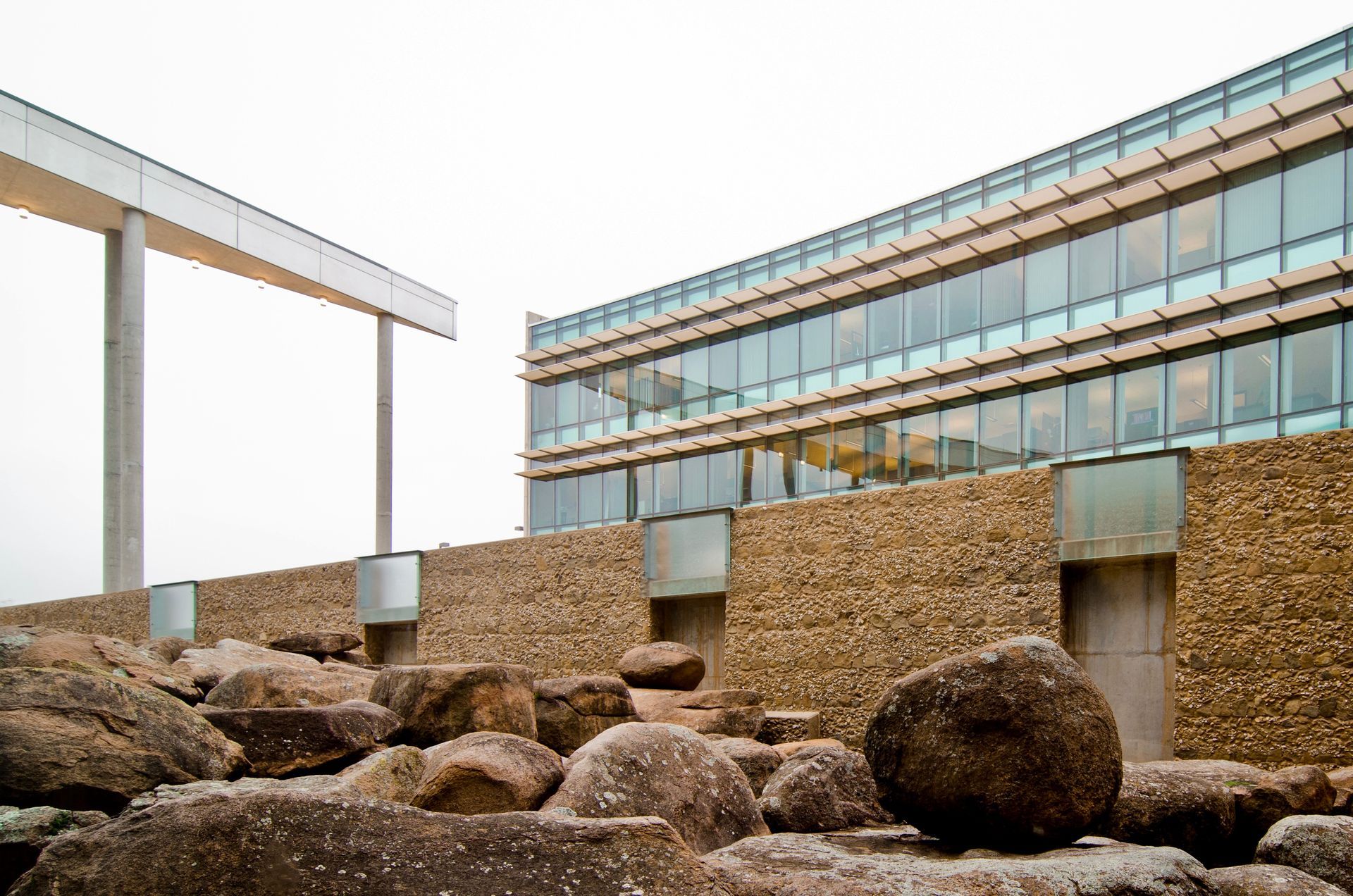 Modern office building with curved glass facade and large boulders in the foreground