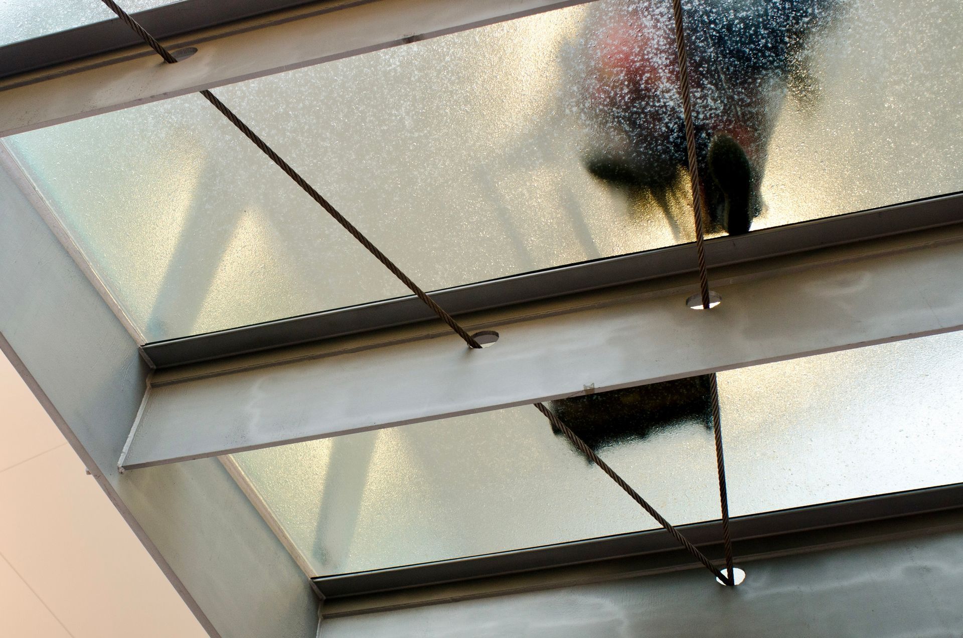 Ceiling view of a person standing behind frosted glass panels in a modern interior